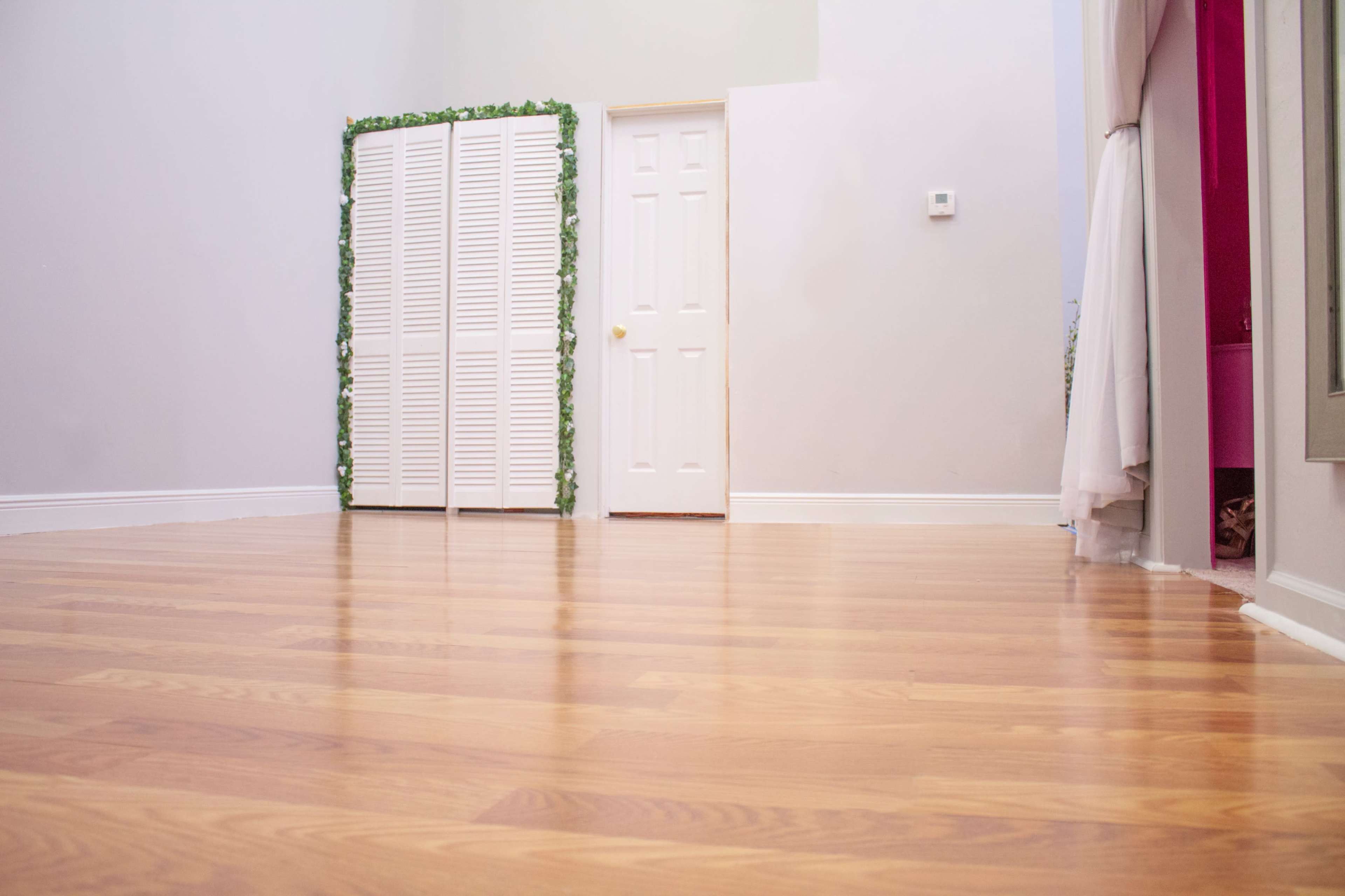 A wooden floor with a partially open white folding screen and a closed door against a light-colored wall.