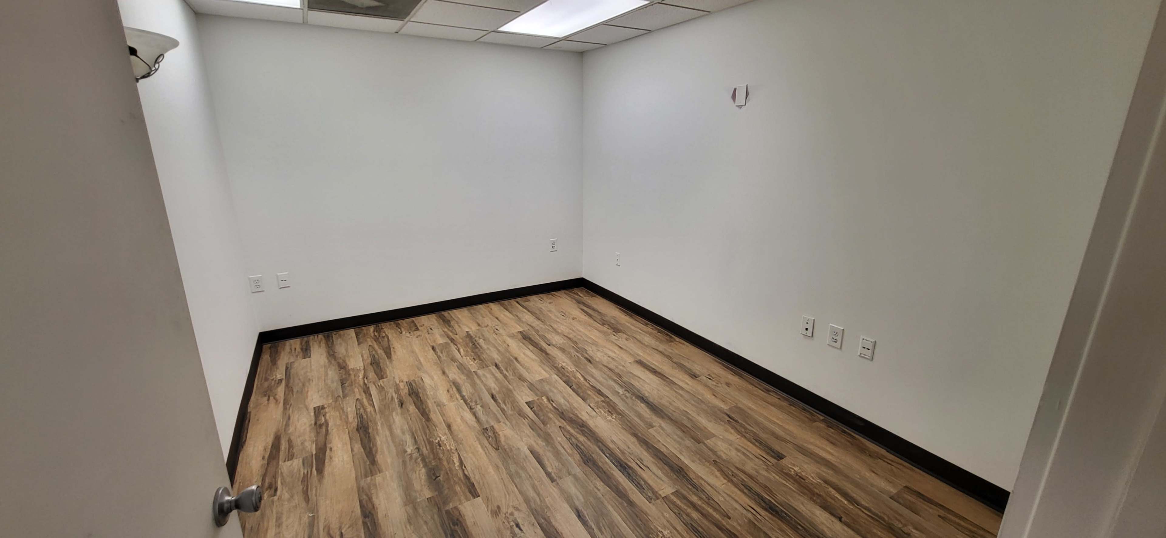 An empty room with light-colored walls and a wooden floor.