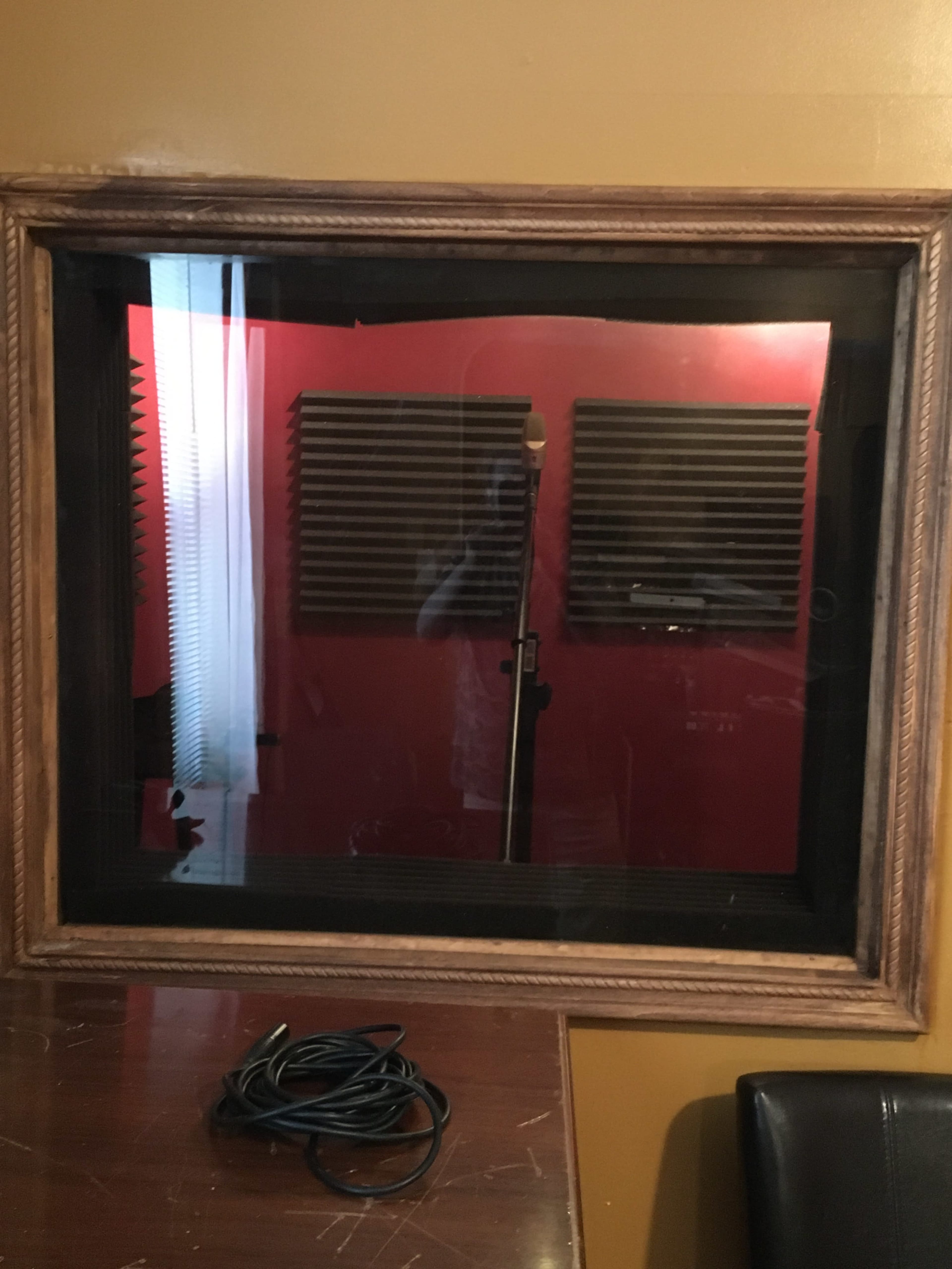 A soundproof recording booth with foam panels on the wall and a microphone stand in the center.