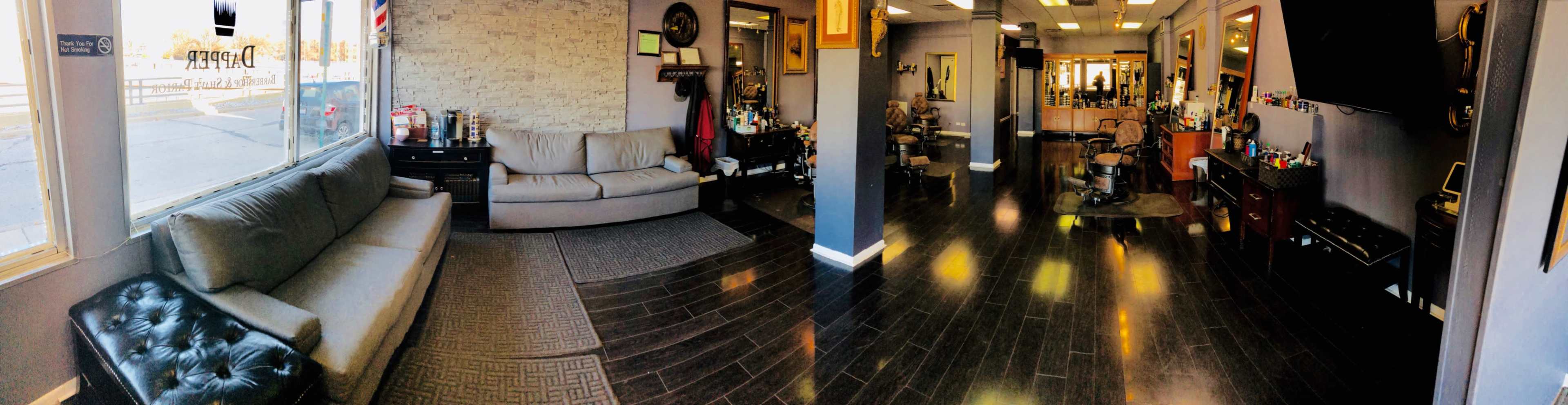 A barbershop interior with a waiting area featuring a couch and a hair cutting area with multiple styling stations.