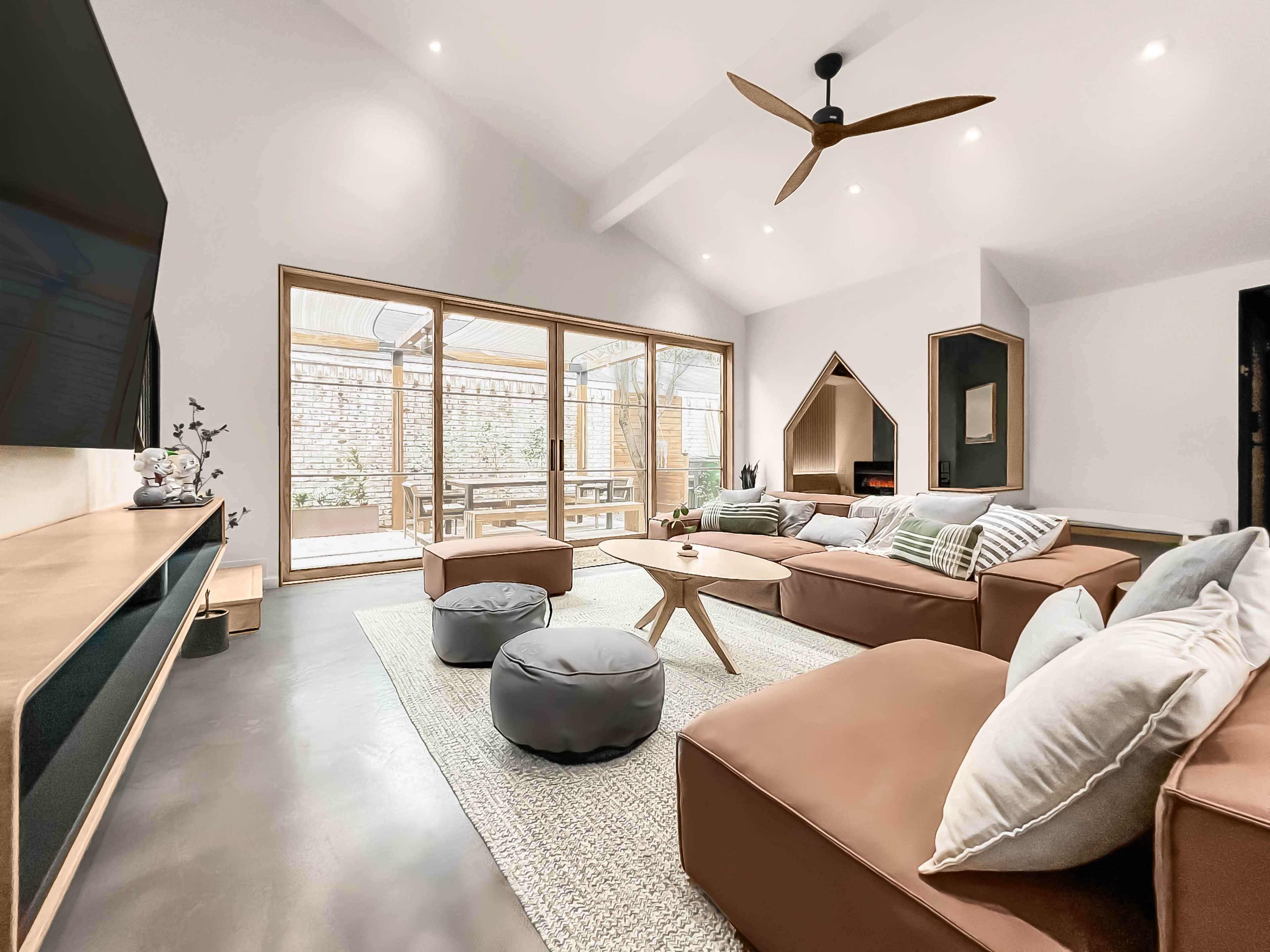 A modern living room with a large sofa, a coffee table, and a view of an outdoor space through large glass doors.