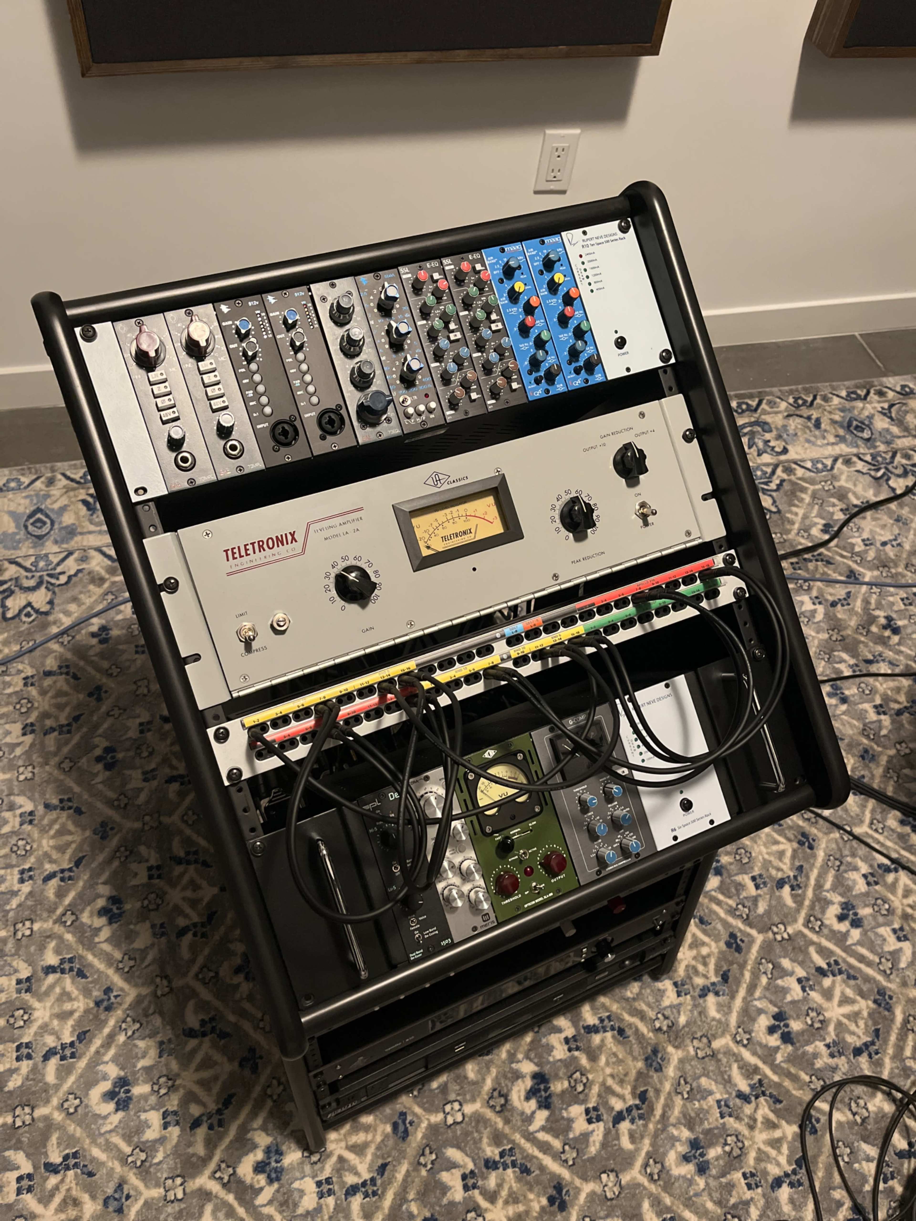 The image shows a rack-mounted audio equipment setup featuring various modules and patch cables arranged in a studio setting.