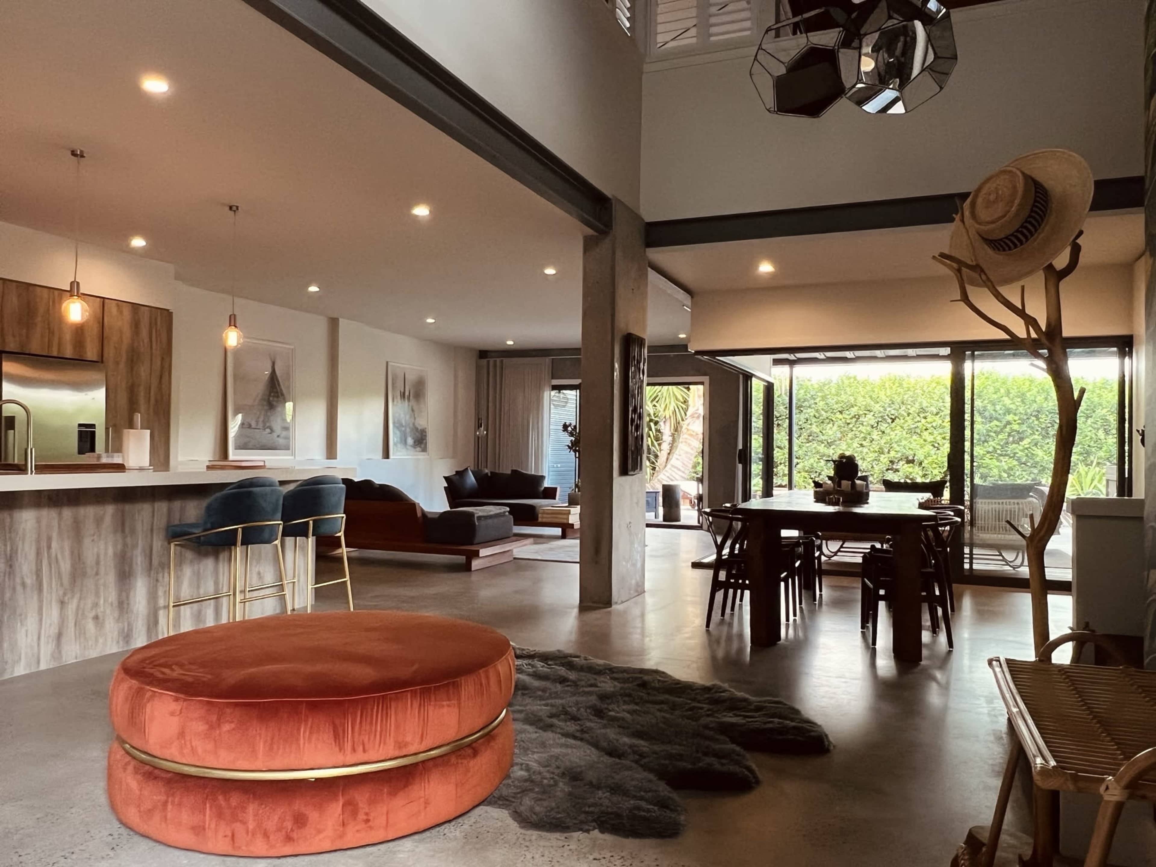 A modern, open-concept living space featuring a kitchen, dining area, and a lounge with large windows allowing for natural light.