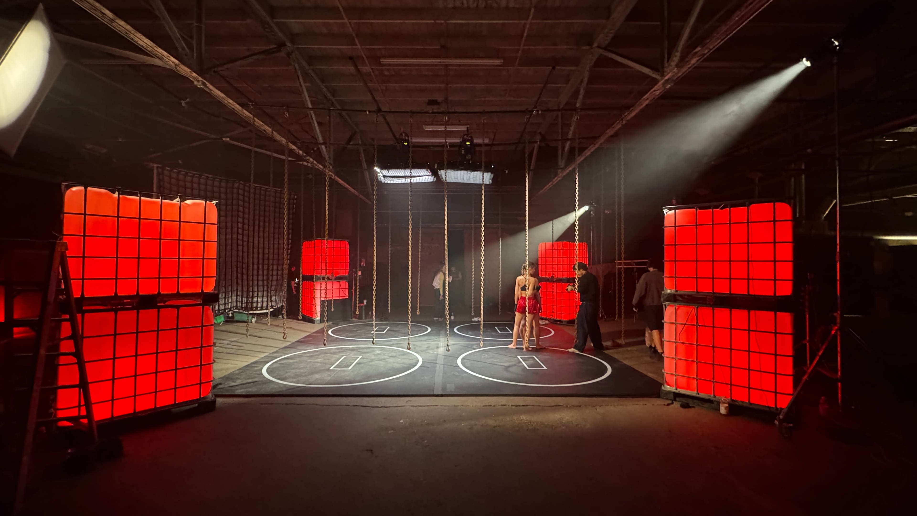 The scene depicts an industrial space with red illuminated cubes arranged around a circular floor design and several people interacting within the area.
