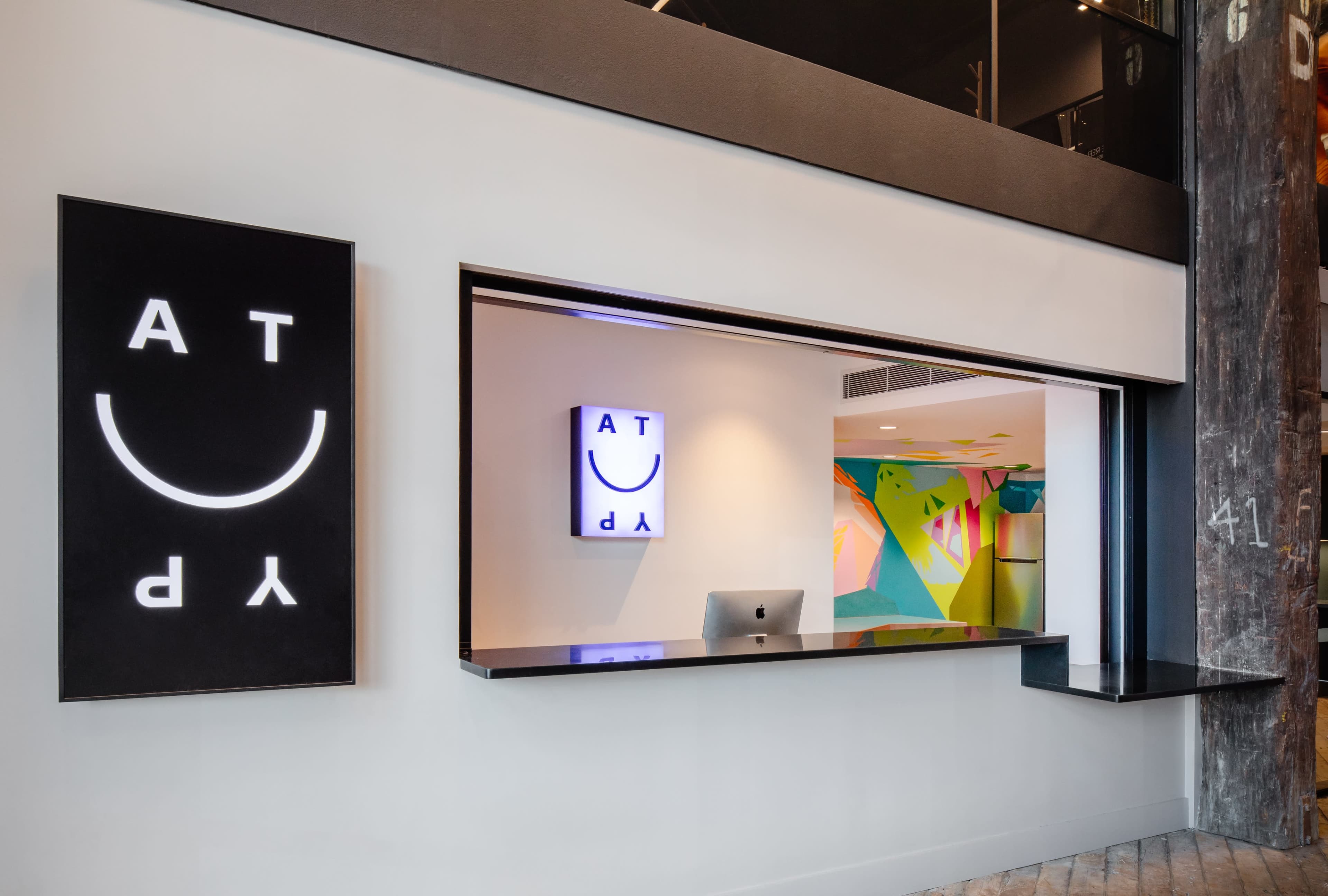 The image shows a modern reception area with a sleek black desk and colorful wall art visible behind it.