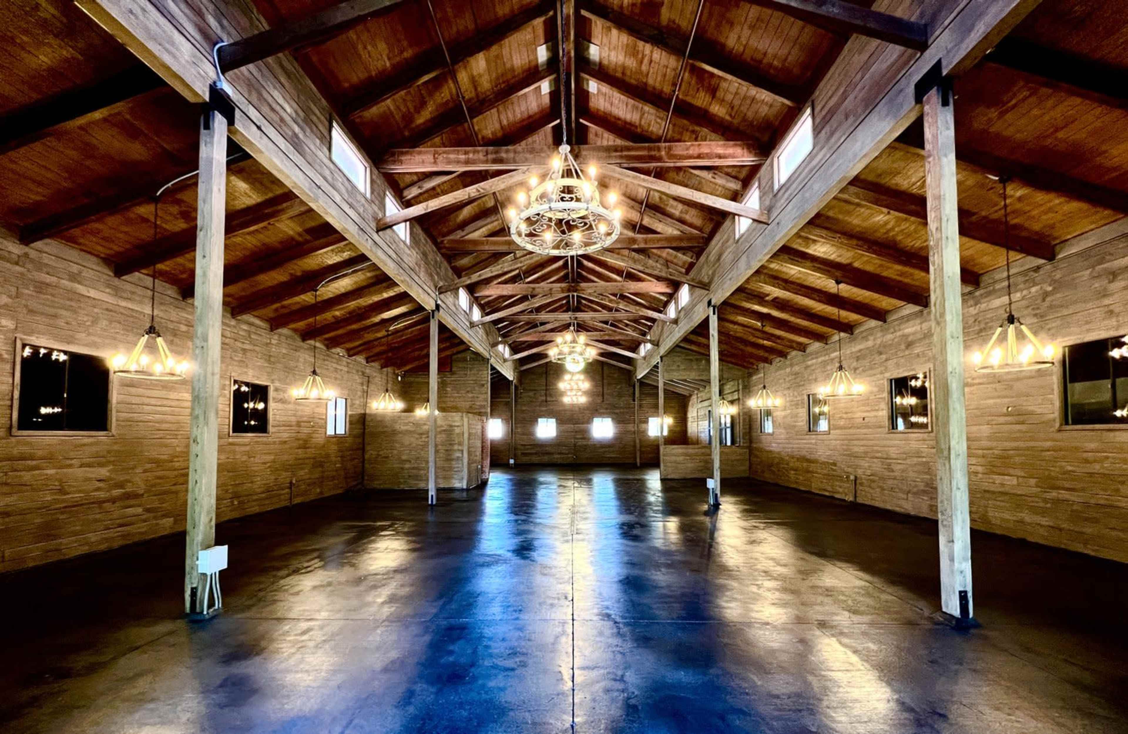 A large, open wooden space with high ceilings, wooden beams, and pendant lighting.
