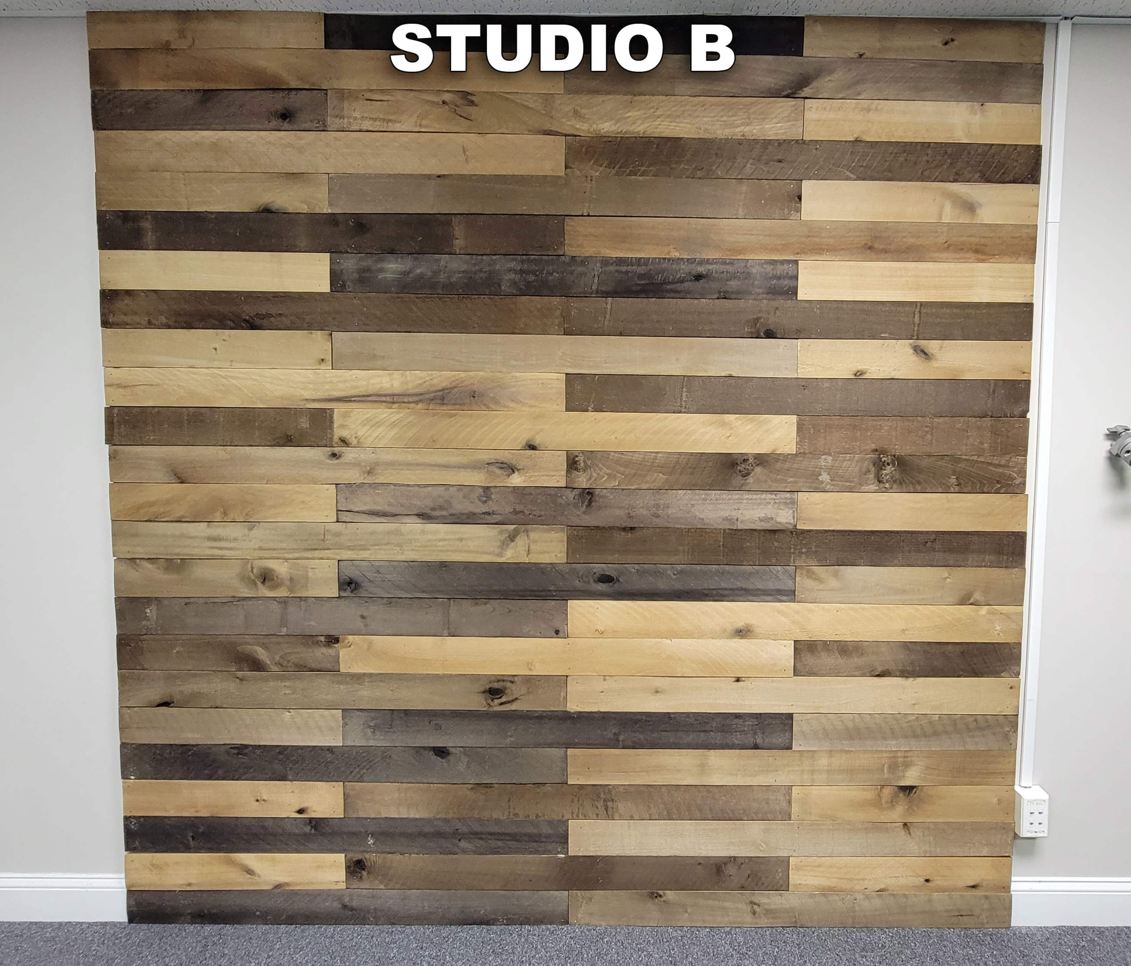A wall made of horizontally arranged wooden planks in various shades, labeled "STUDIO B" at the top.