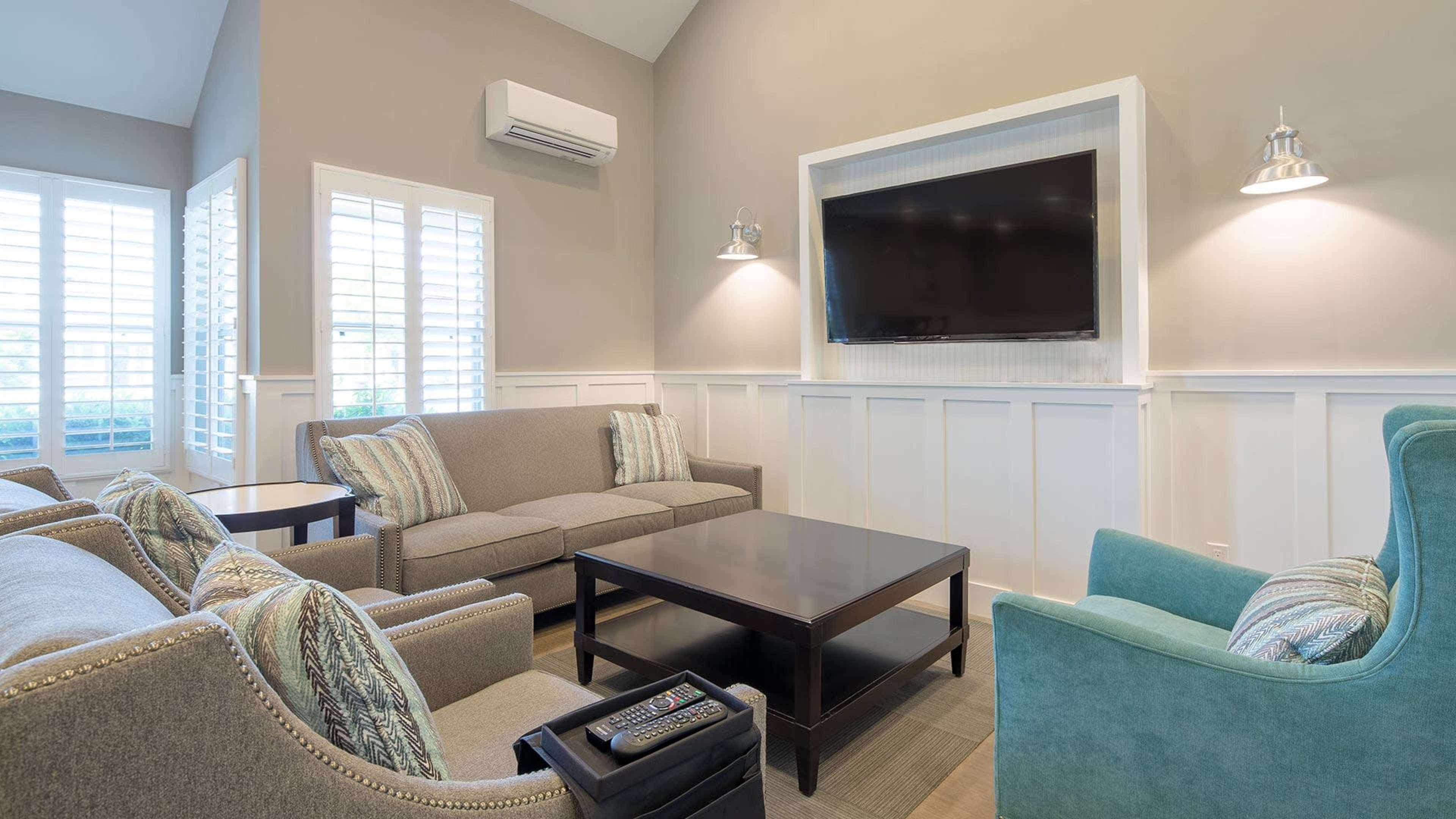 A modern living room with a sofa, armchairs, a coffee table, and a wall-mounted television.