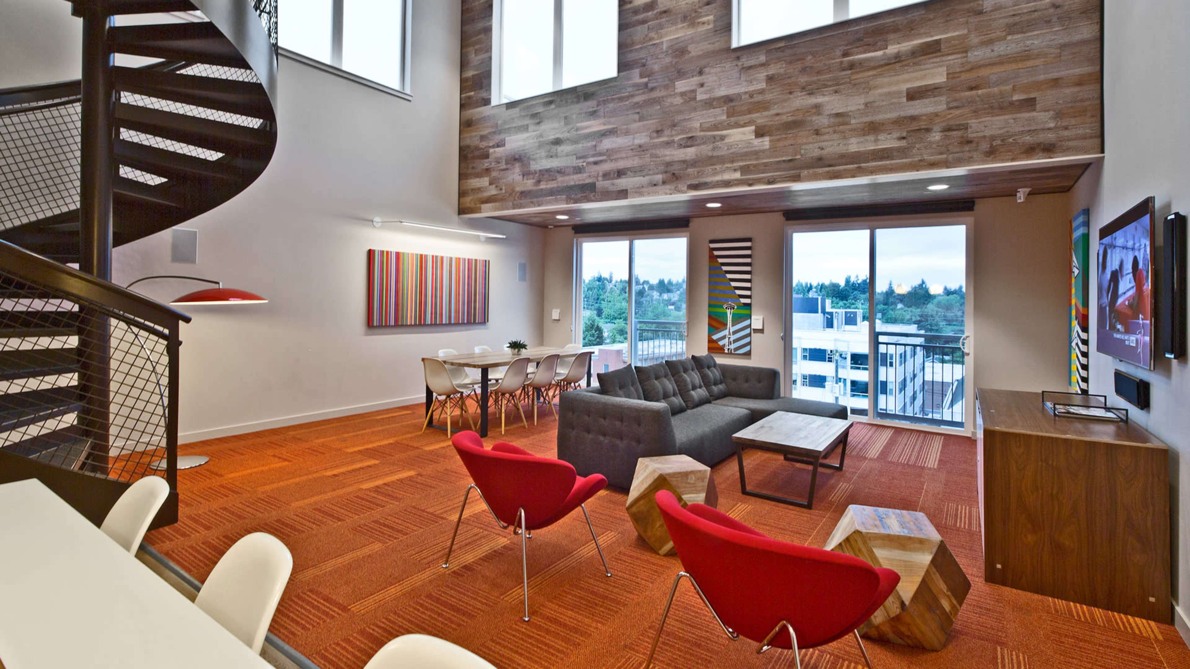 The image shows a modern living space featuring a spiral staircase, large windows, a sectional sofa, a dining area, and wooden accent walls.