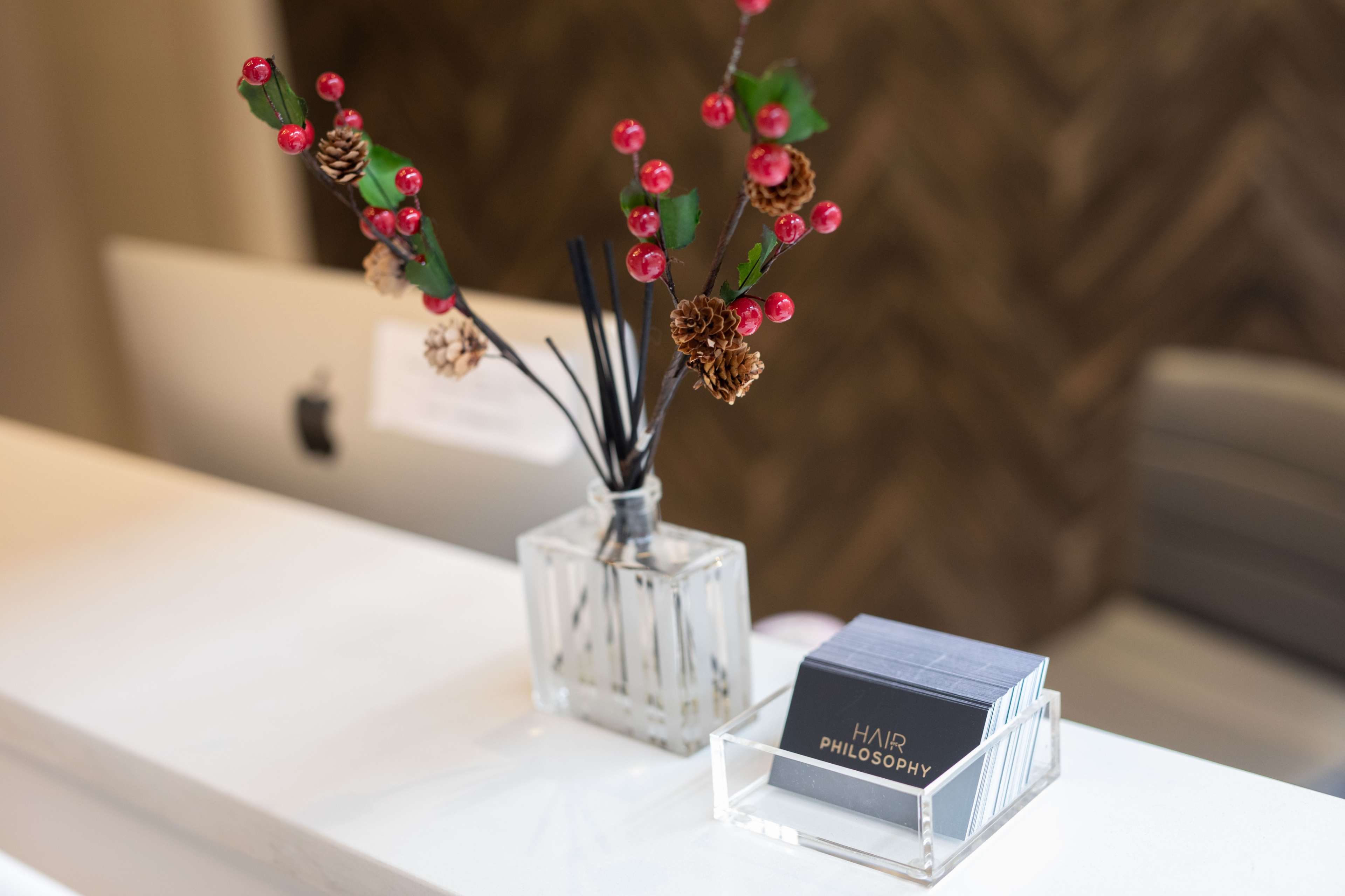 A clear glass vase with decorative flowers and a holder containing business cards sits on a white counter.