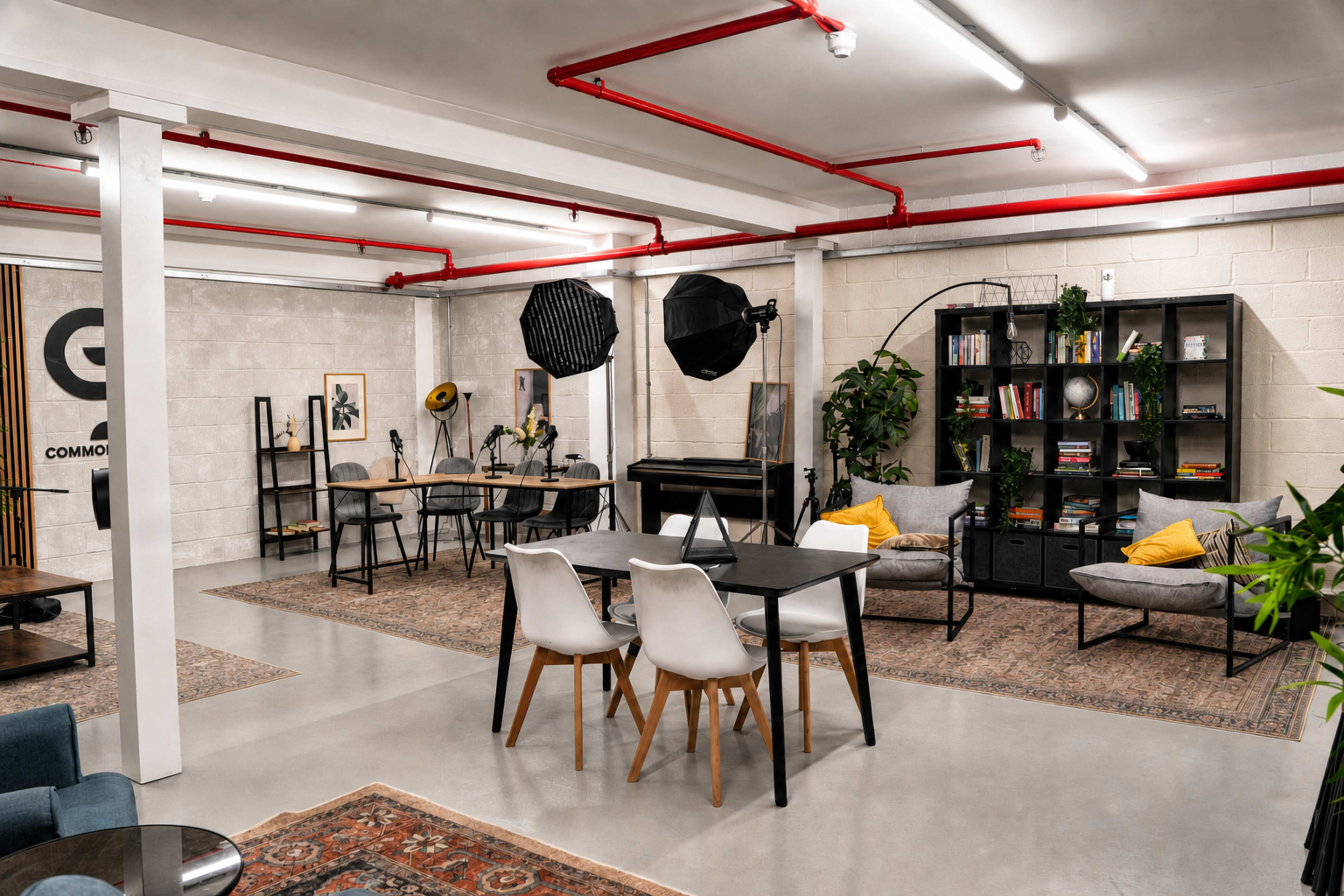 The image shows a spacious, modern coworking area featuring several seating options, a piano, and photography equipment.