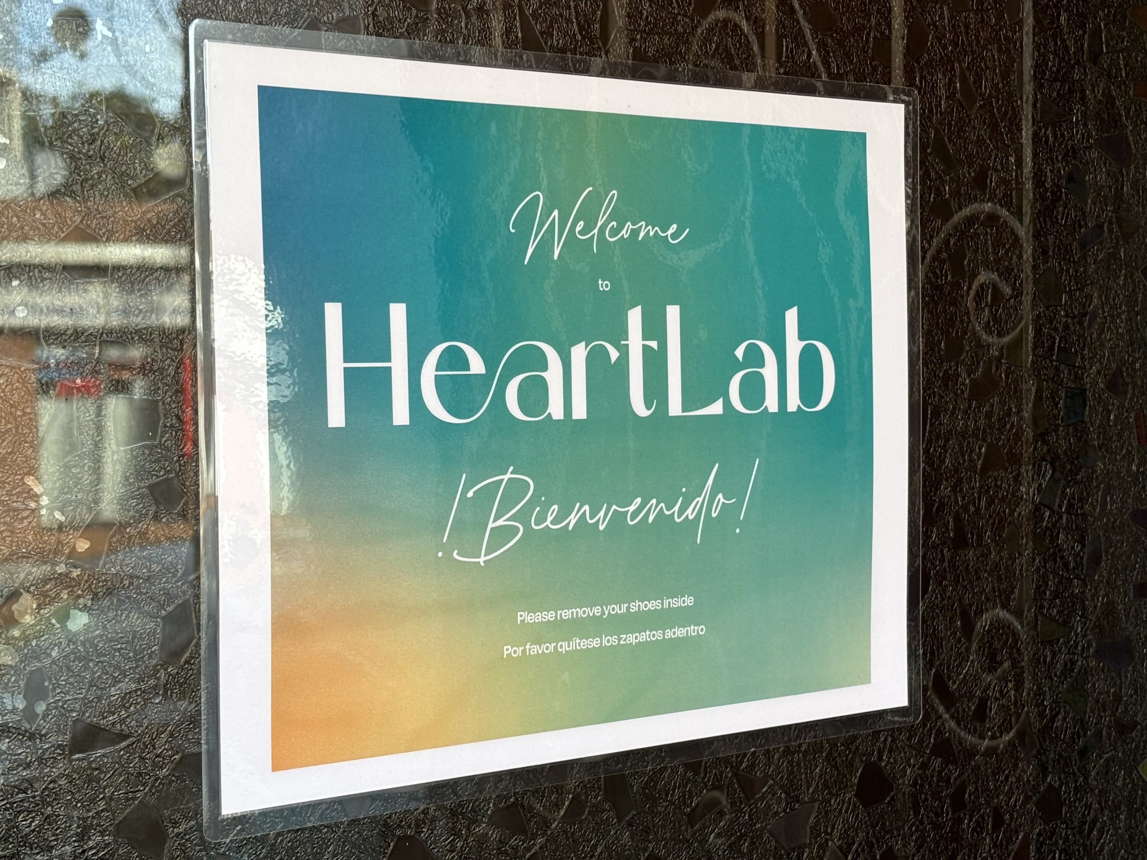 A sign at the entrance of HeartLab invites visitors and requests them to remove their shoes inside.