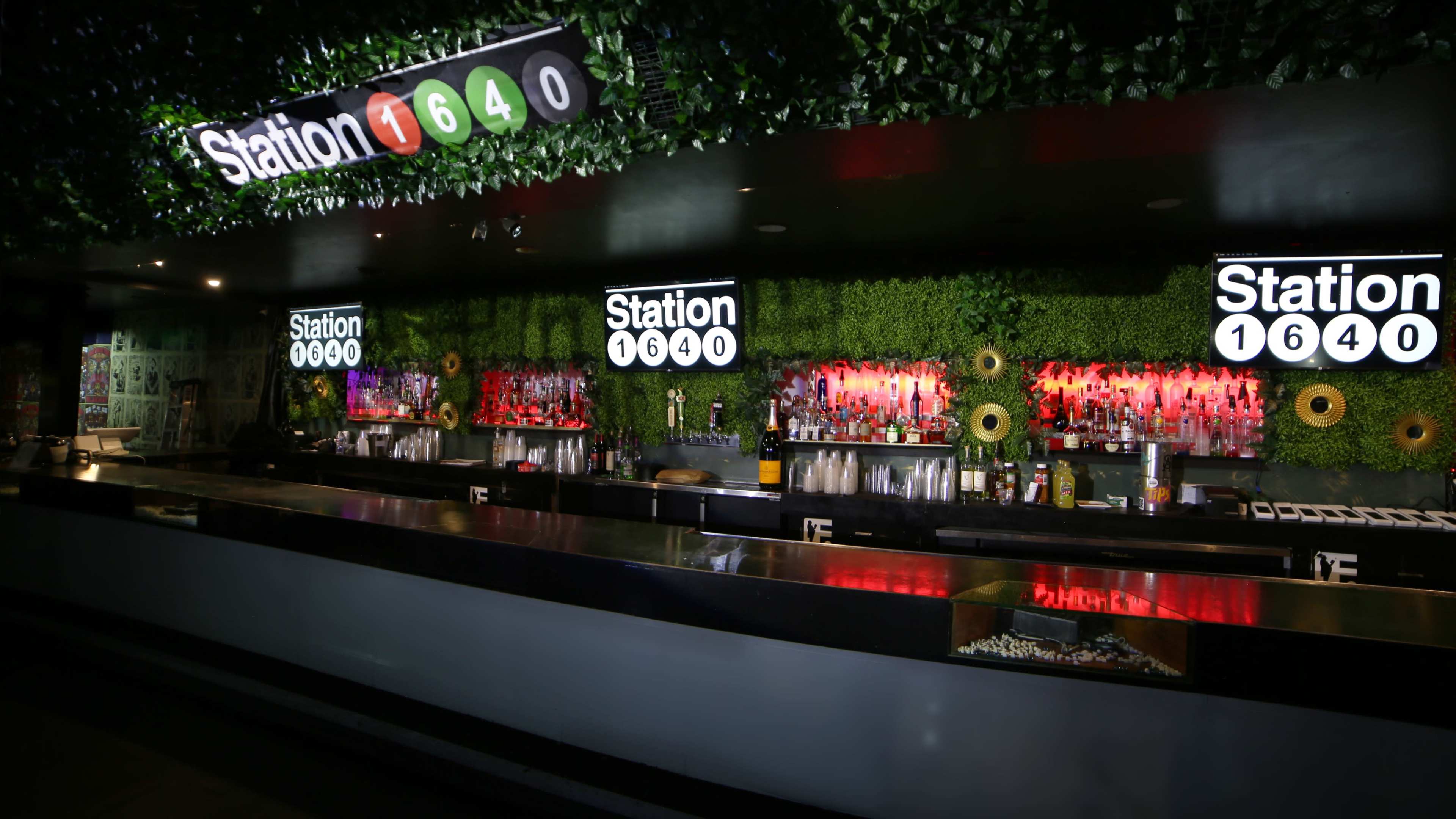 A modern bar featuring a green wall and illuminated signage with the name "Station 1640" prominently displayed.