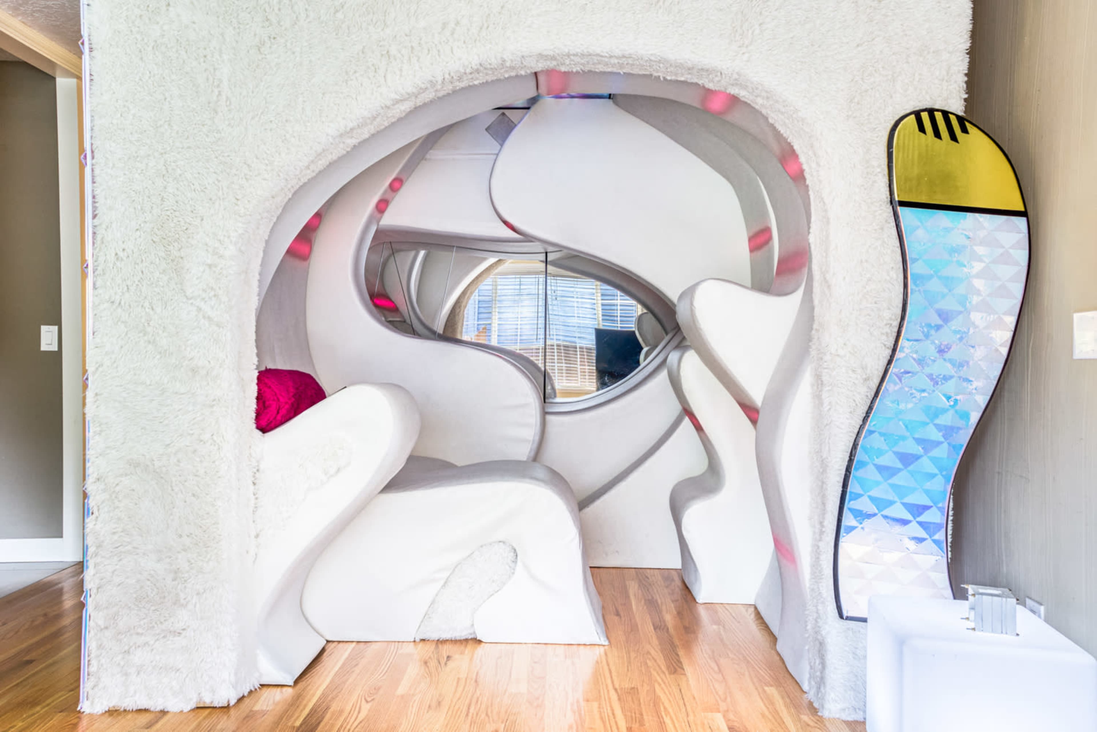 A futuristic, soft-walled alcove with a curved seating area and decorative elements in a cozy room.