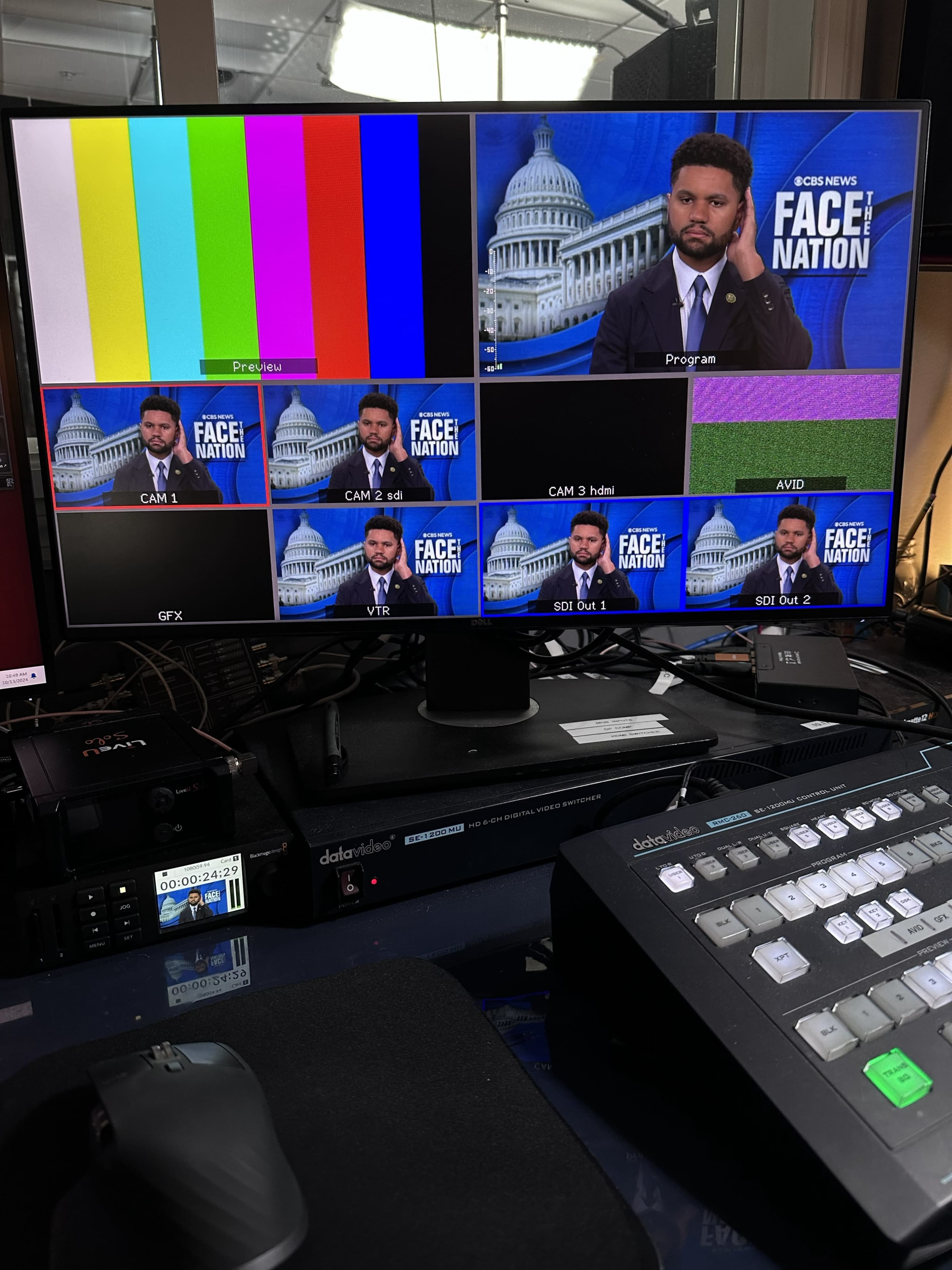 The image displays a computer monitor with multiple screens showing a television broadcast setup, including color bars, a host with a backdrop of the U.S. Capitol, and control equipment.