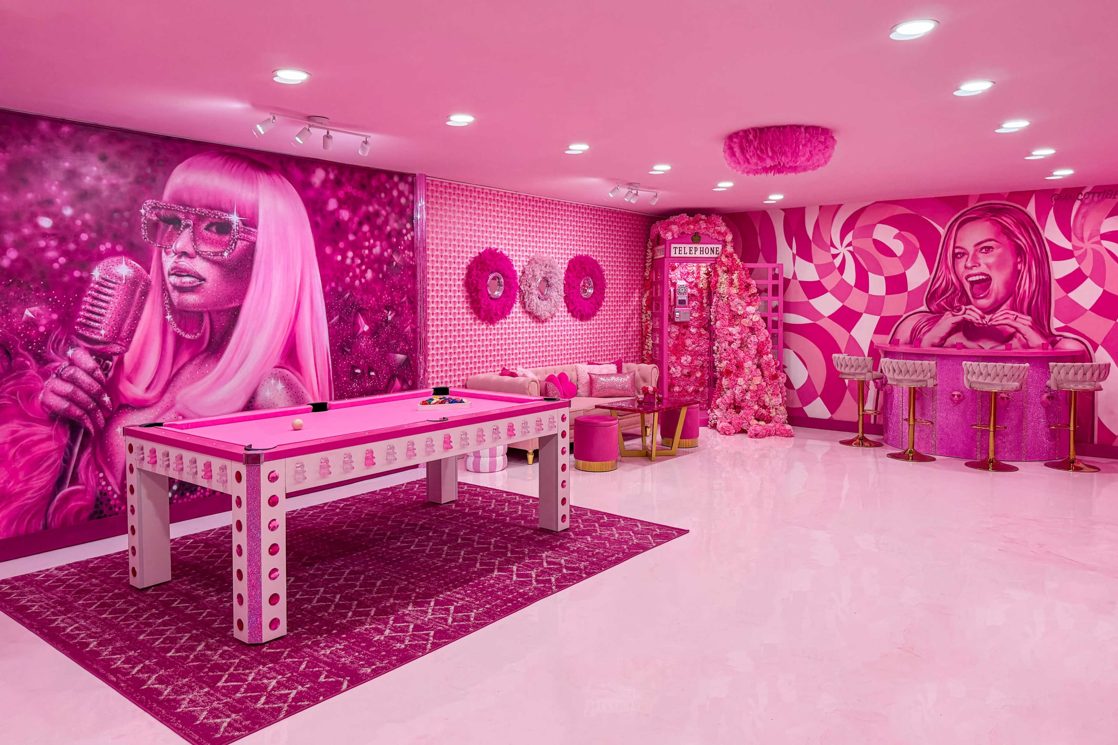 The room features a vibrant pink color scheme with a pool table, decorative wall murals, and stylish seating areas.