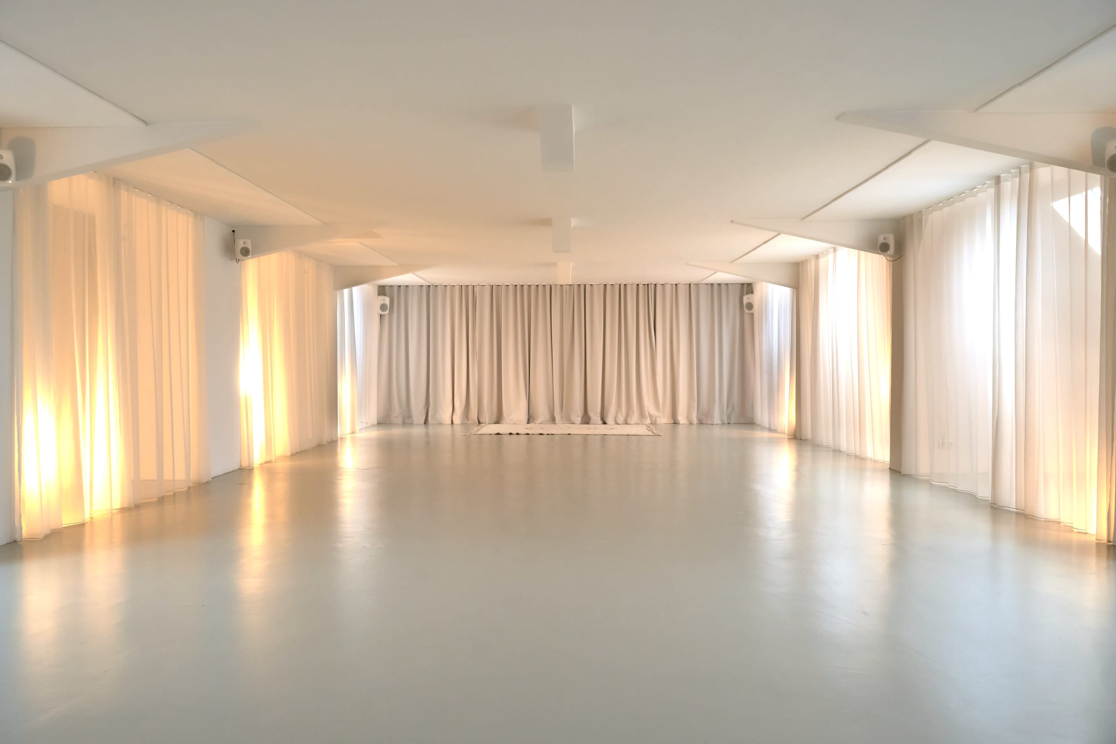 The image depicts a spacious, minimalist room with white curtains and soft illumination.