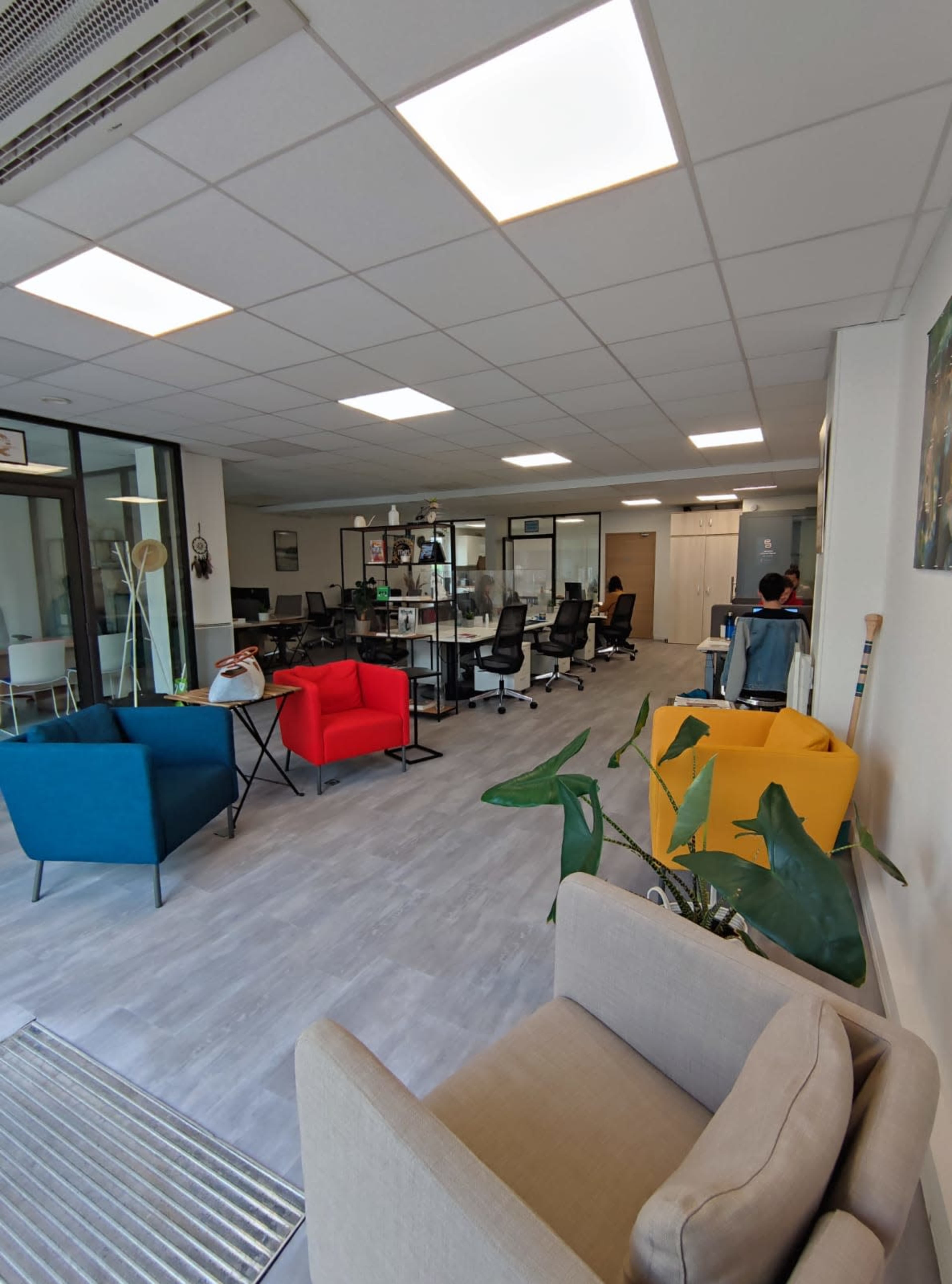 An office space with colorful seating areas, desks, and a reception area.