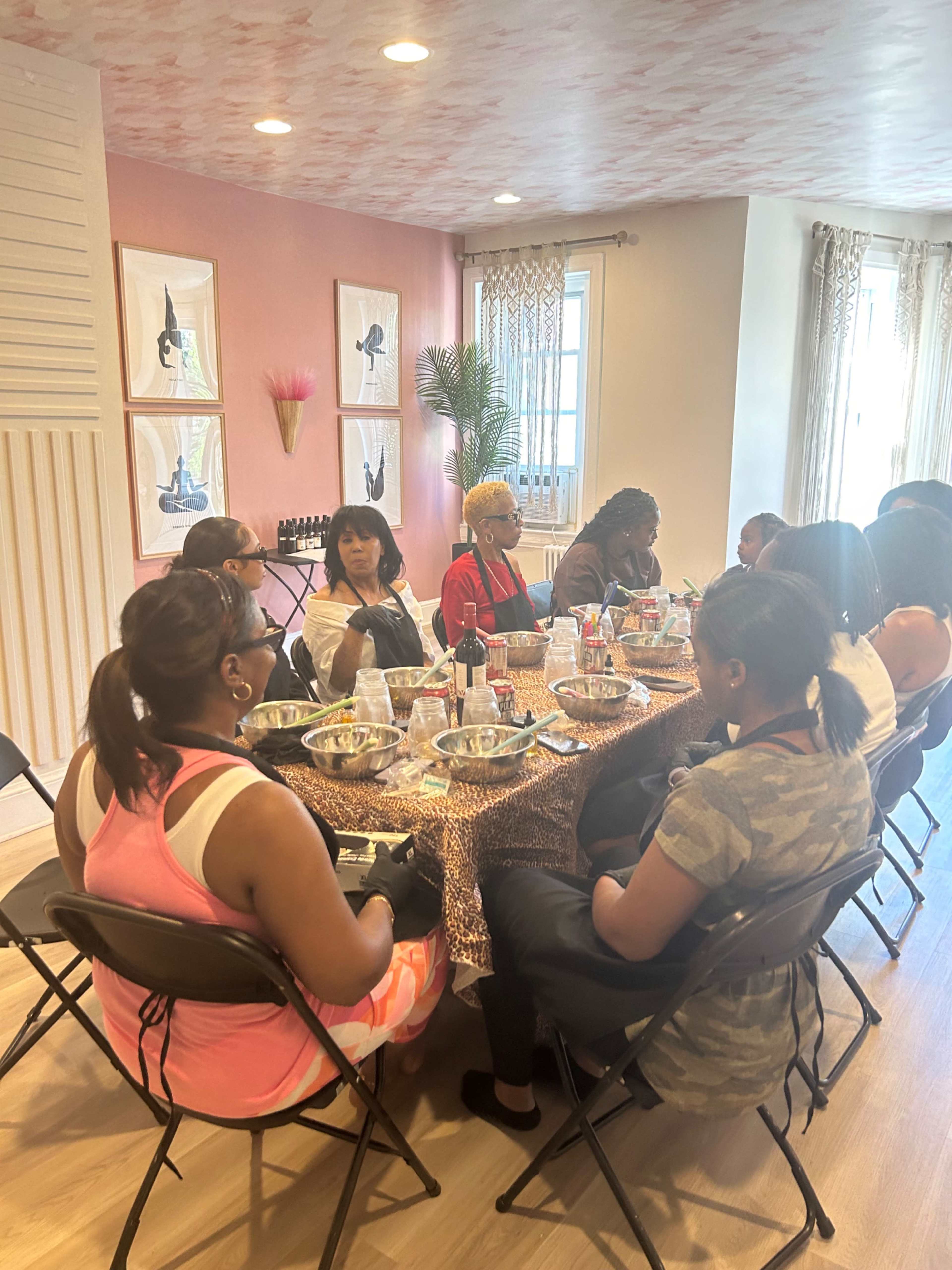 A group of people sits around a table in a well-lit room, engaged in an activity involving bowls and various materials.