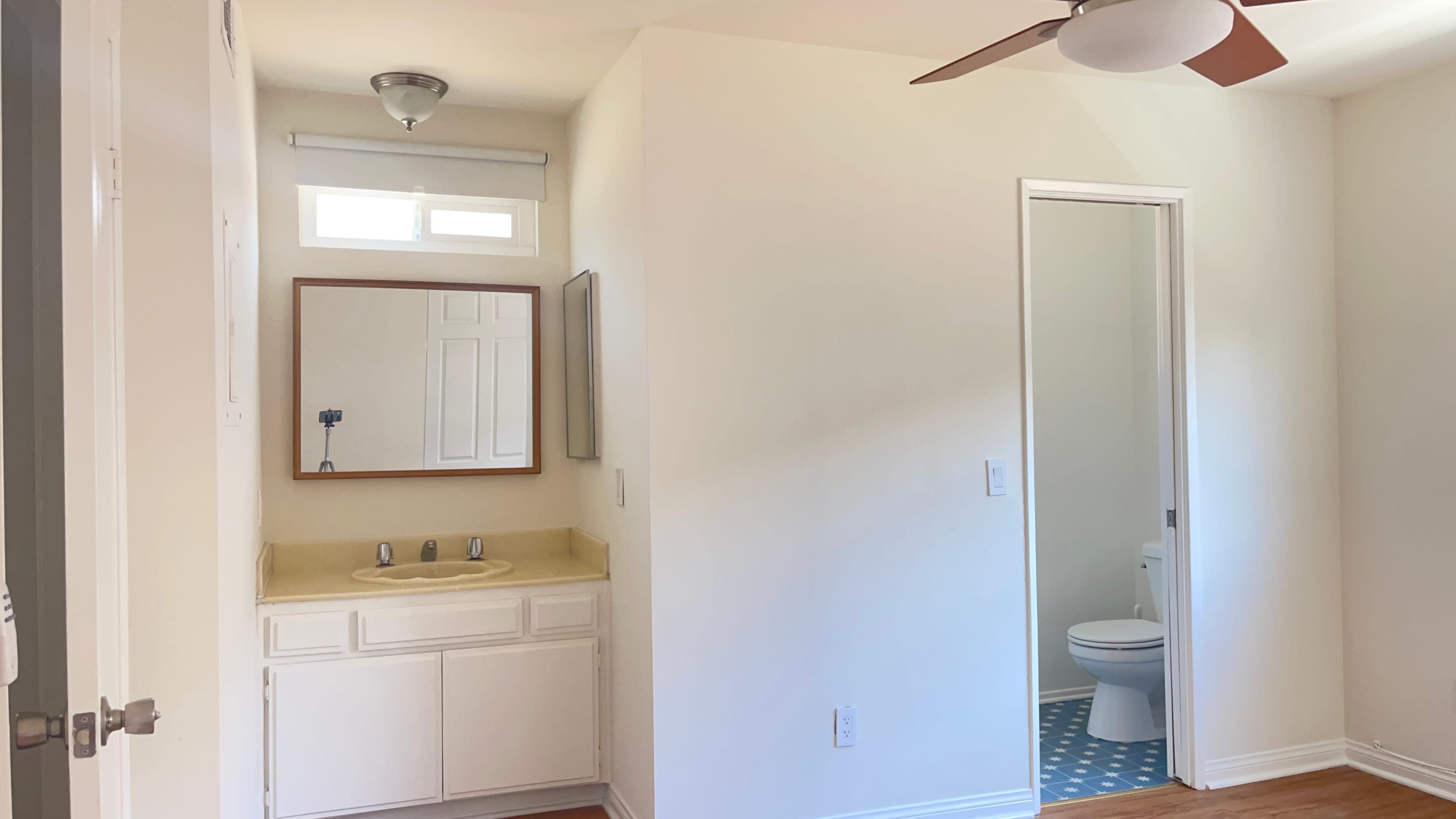 A bathroom area featuring a sink with a mirror and a separate entrance to a toilet compartment.