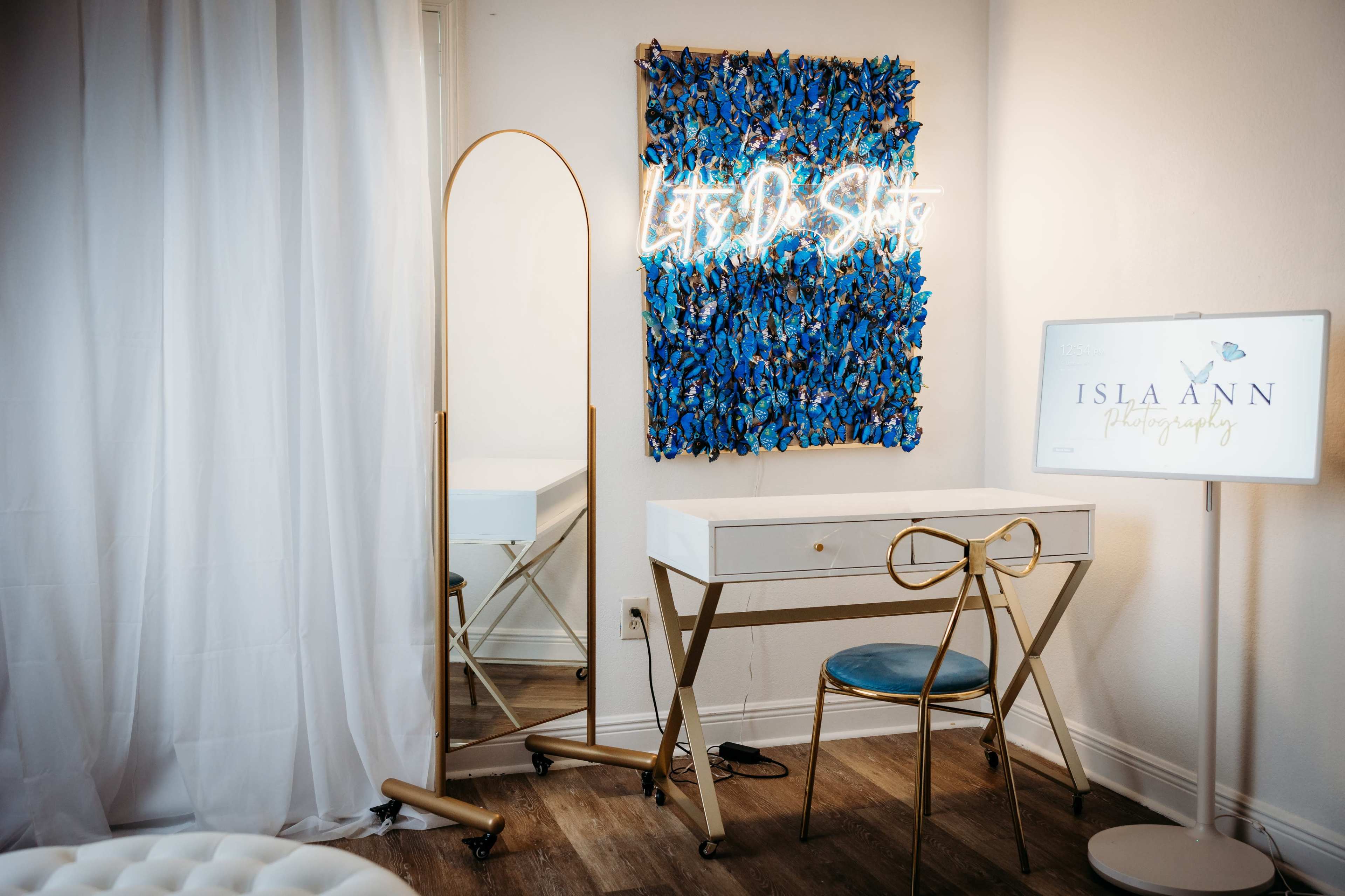 A dressing area with a mirror, a decorative wall piece, and a stylish desk featuring a bow-shaped chair.