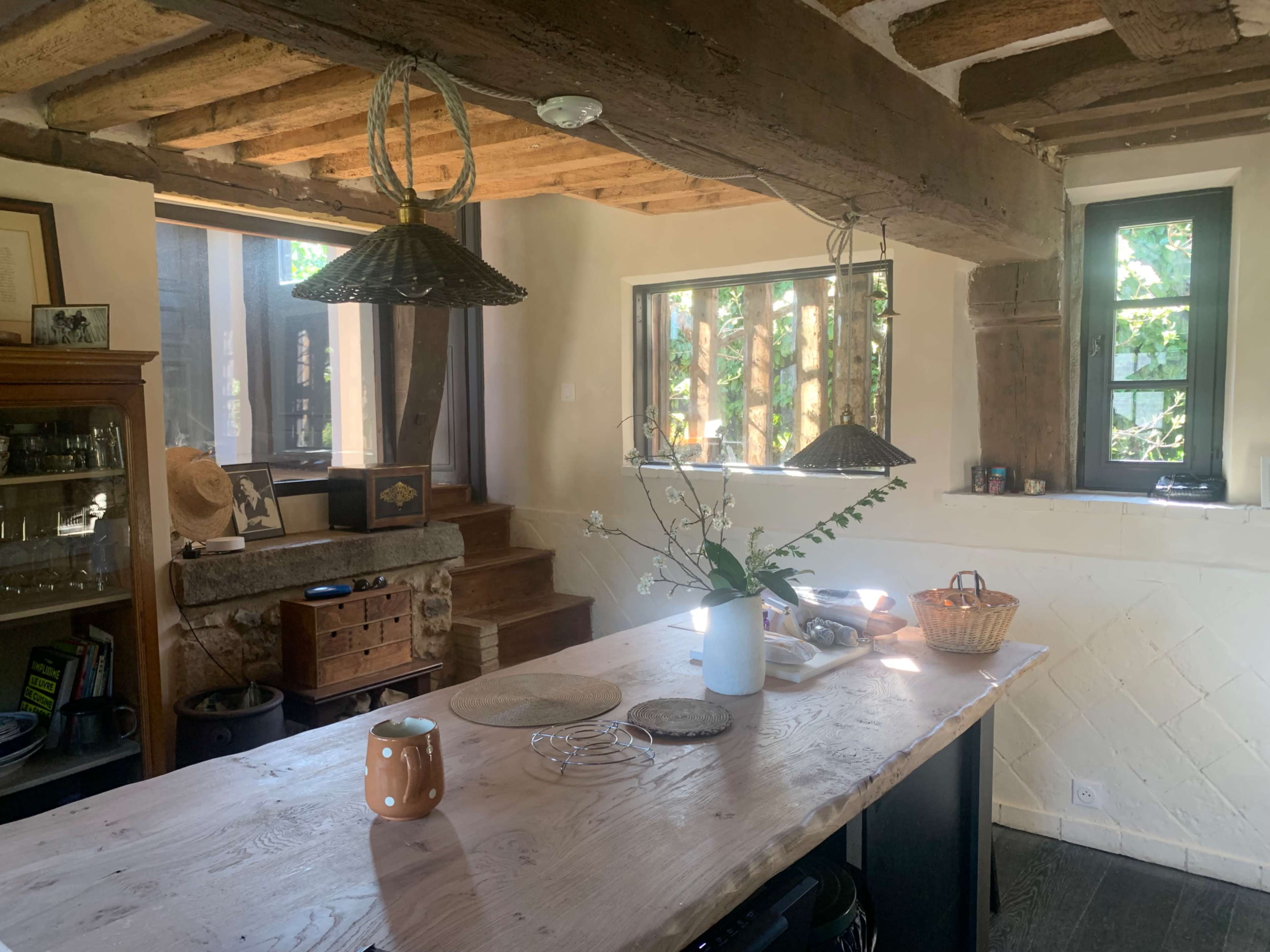 A spacious kitchen features wooden beams, an island countertop, and windows allowing natural light to illuminate the interior.
