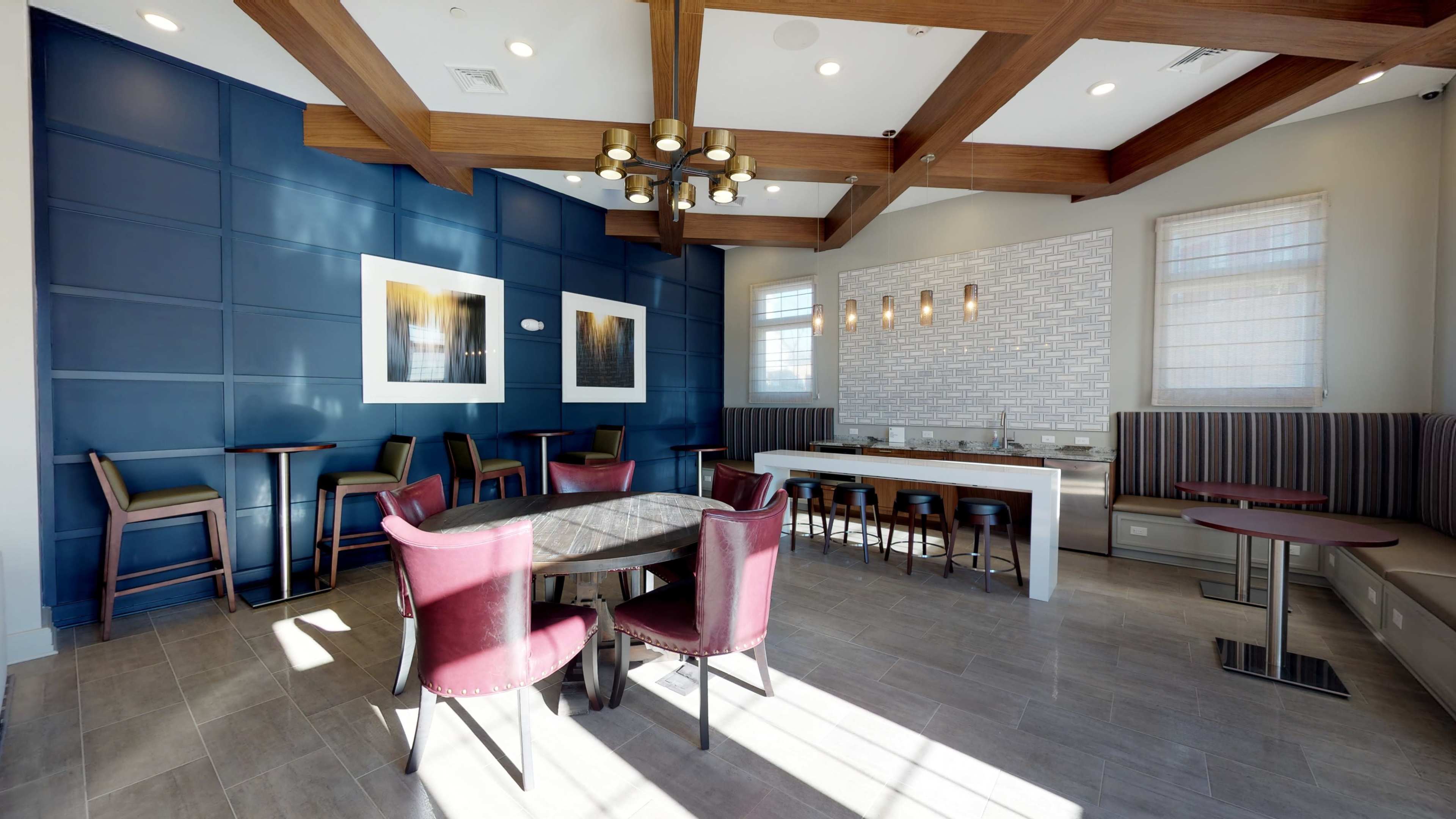 A modern dining area featuring a table with chairs, a bar counter, and decorative wall panels in blue and white.