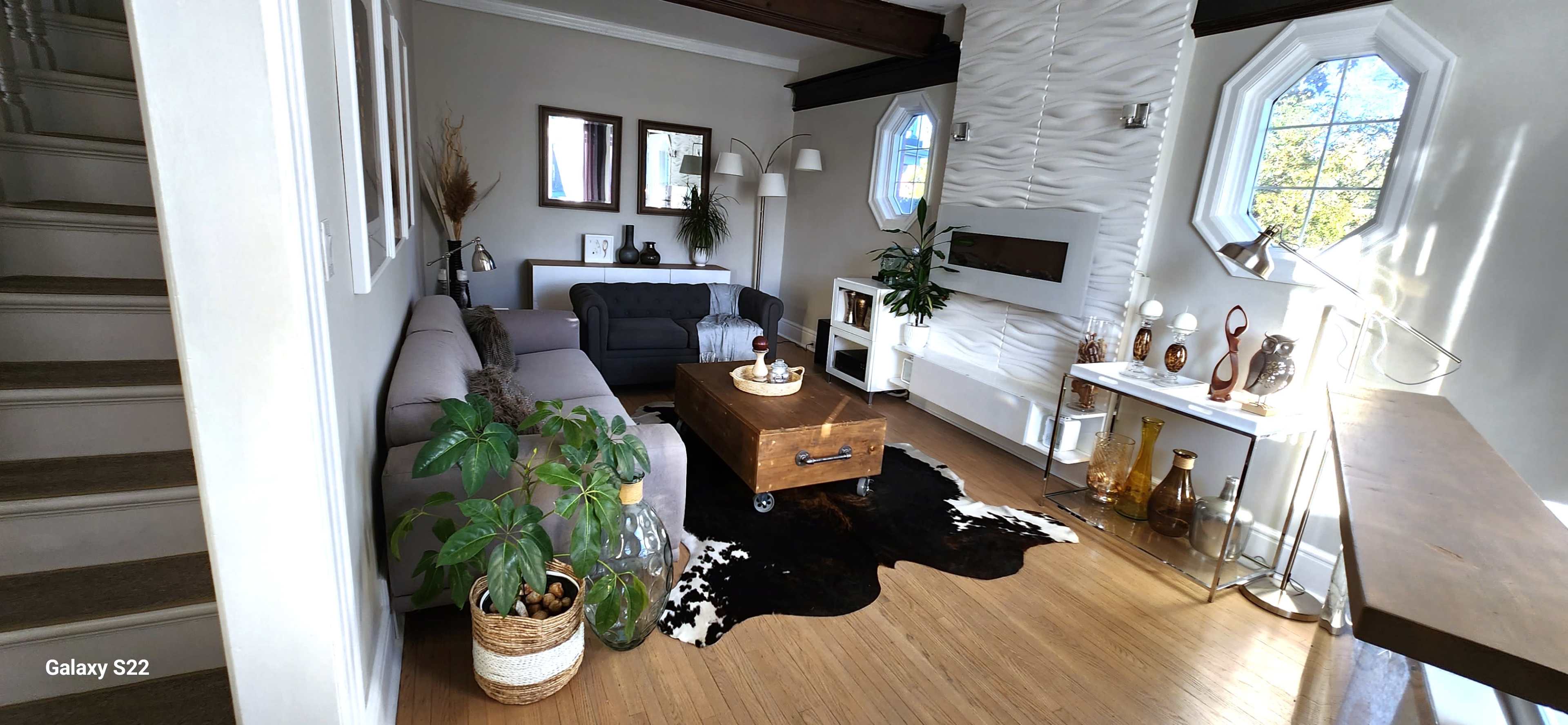 A modern living room with a sectional sofa, a wooden coffee table, decorative vases, and a stylish wall featuring a fireplace and a textured design.
