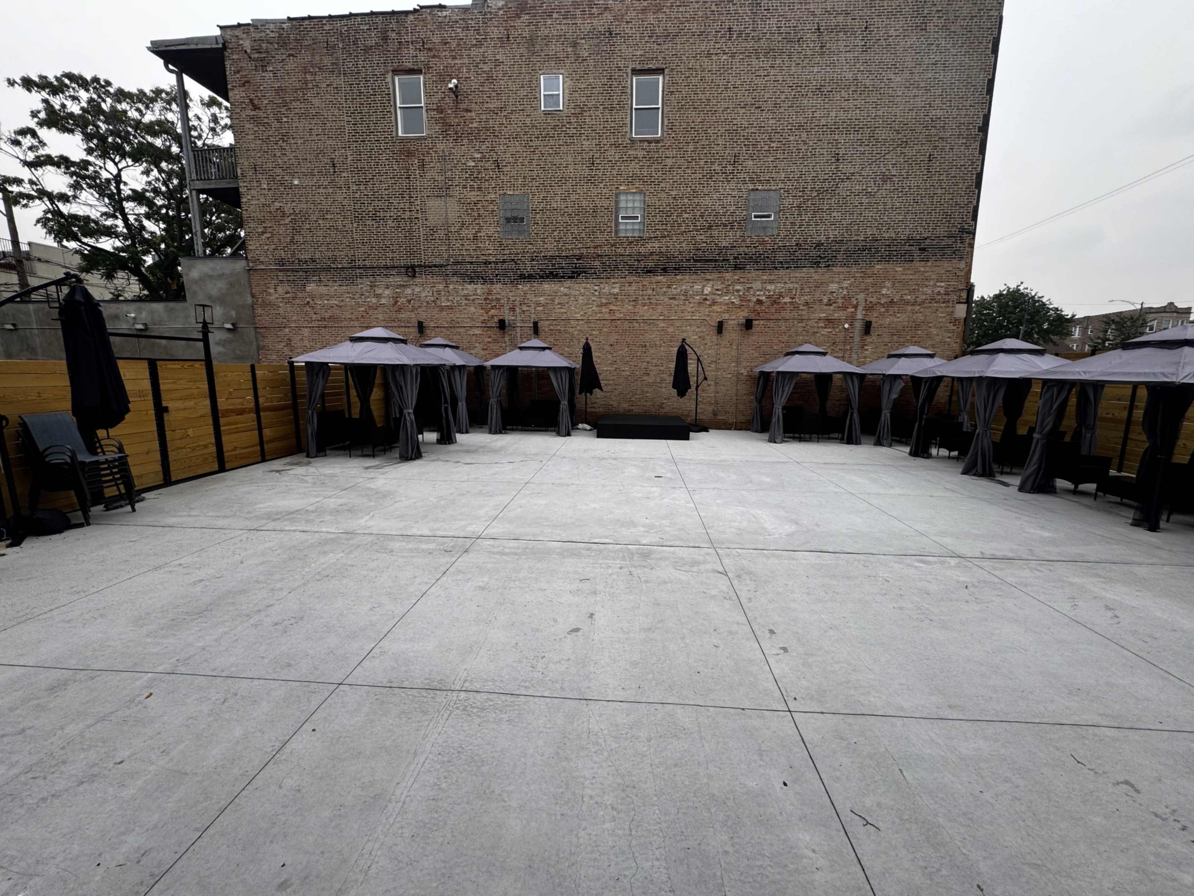 The image shows a spacious outdoor area with several tents and a brick building in the background.