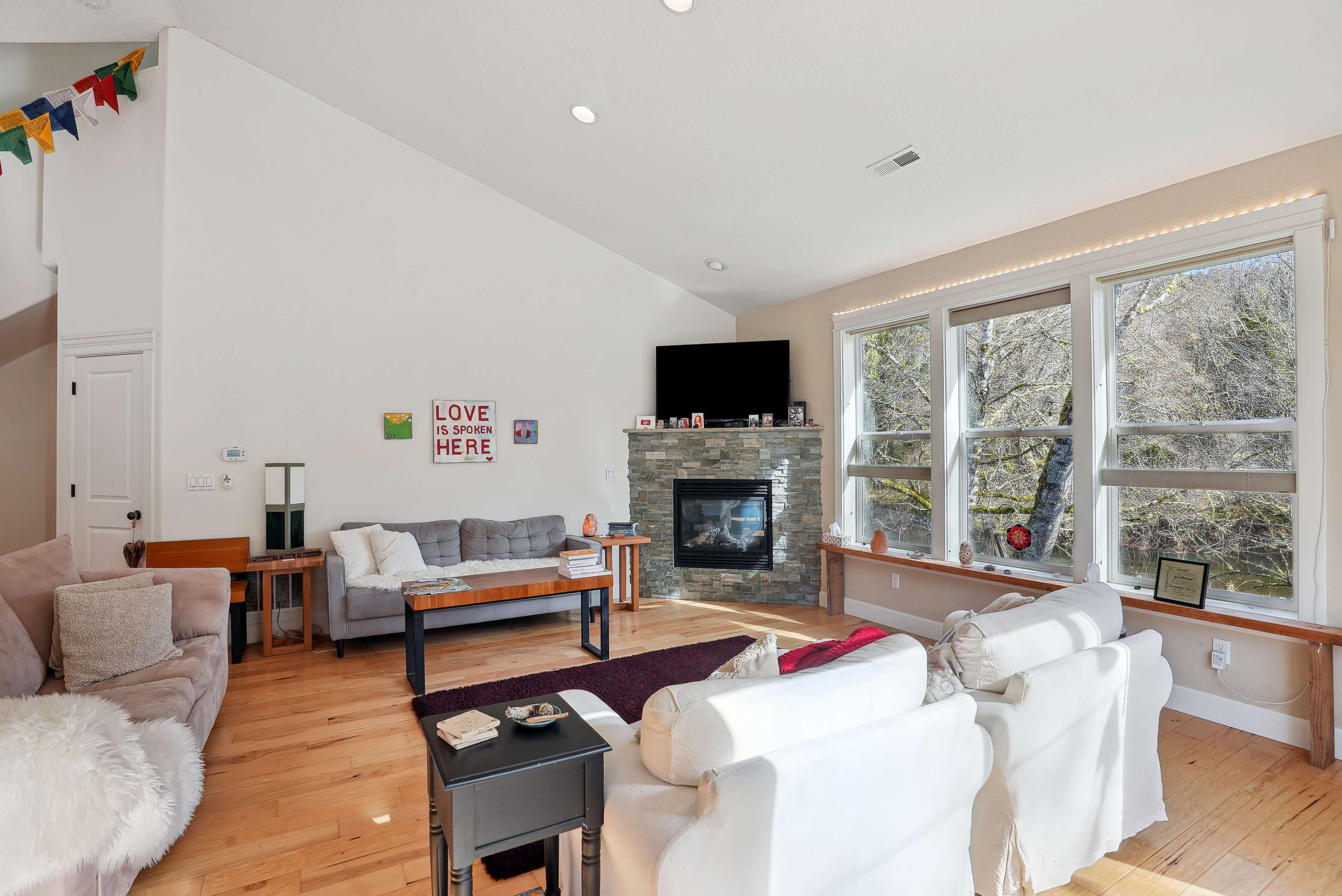 The living room features a fireplace, a large window with natural light, and a mix of comfortable seating arrangements.