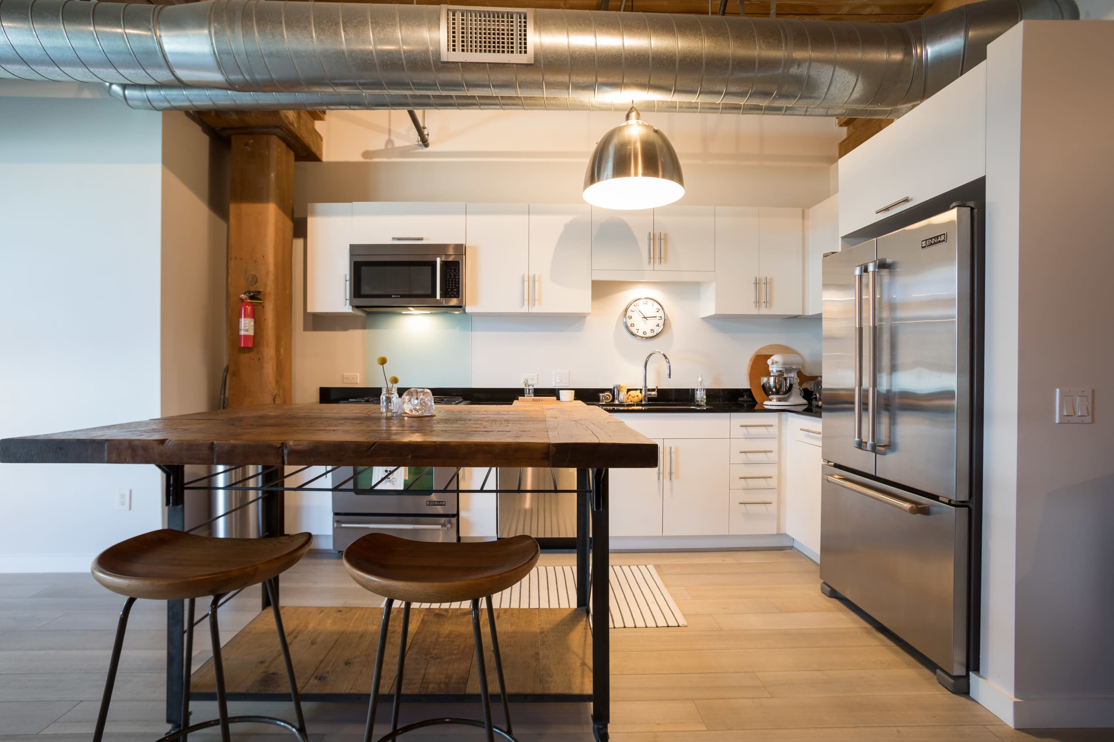 The image shows a modern kitchen with a large wooden island, stainless steel appliances, and white cabinetry.