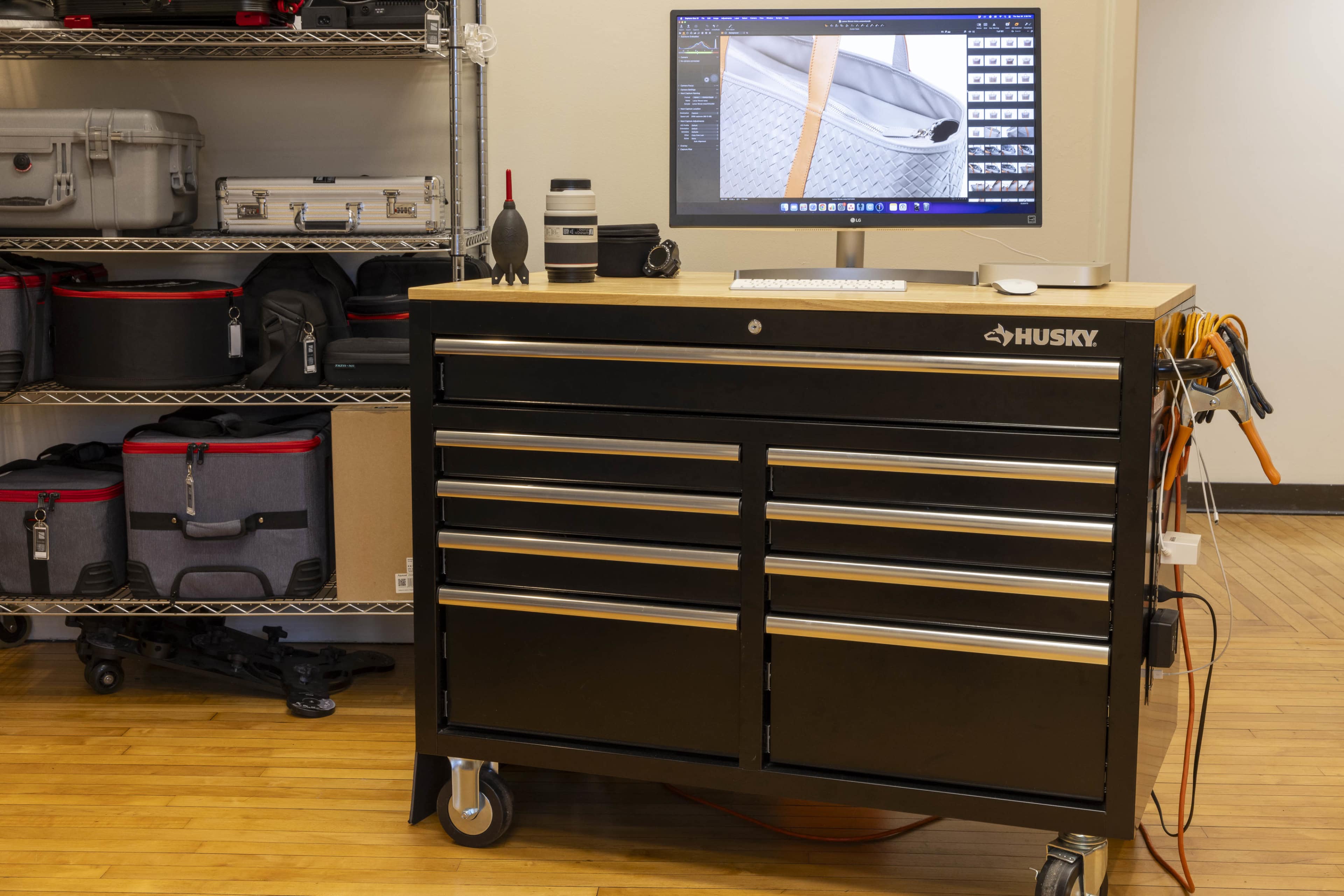 A black tool chest with multiple drawers is positioned on wheels in front of a computer monitor displaying a design software interface.