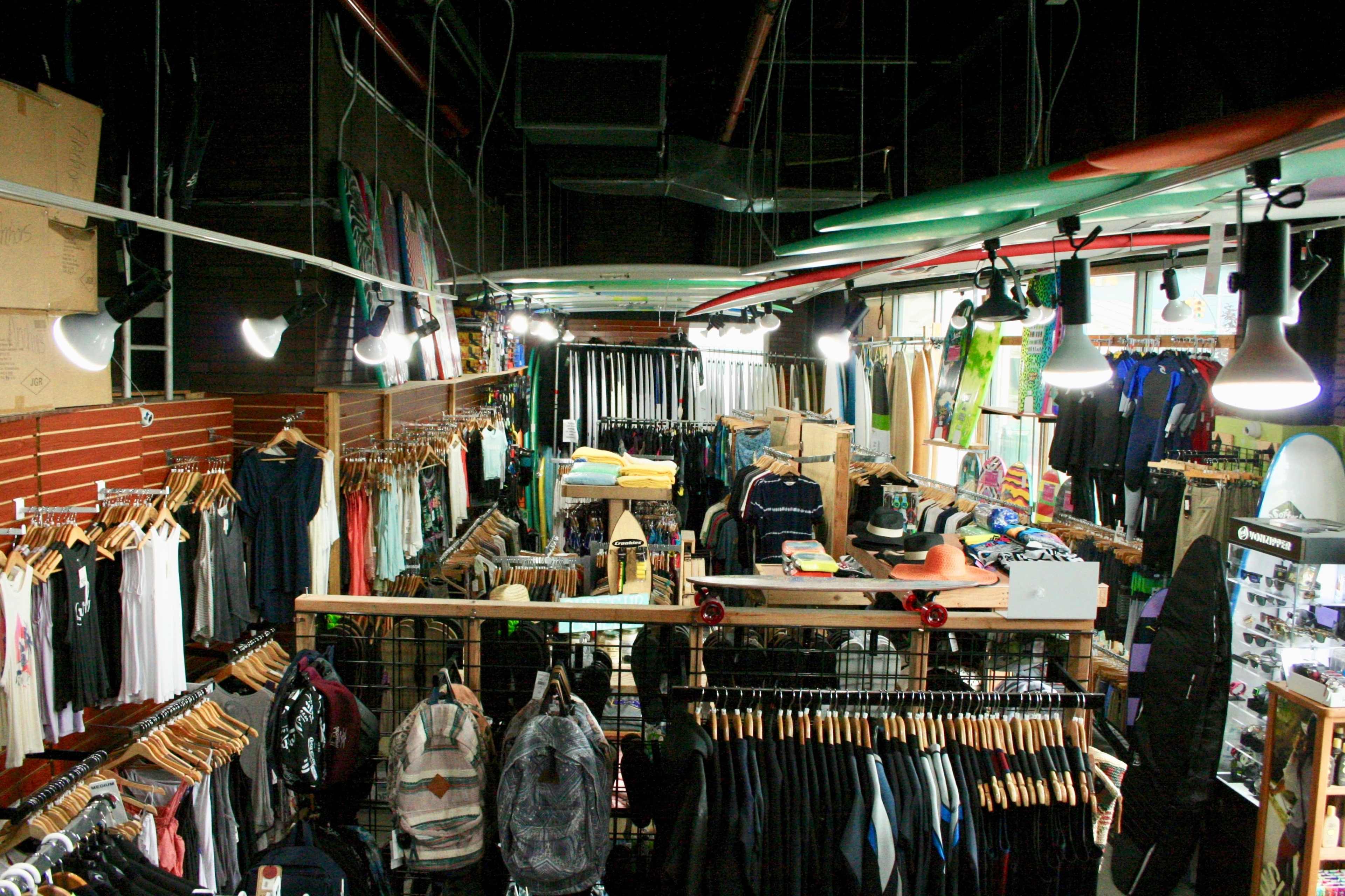 The image shows an organized retail store interior filled with clothing racks, backpacks, and various merchandise displayed on tables.