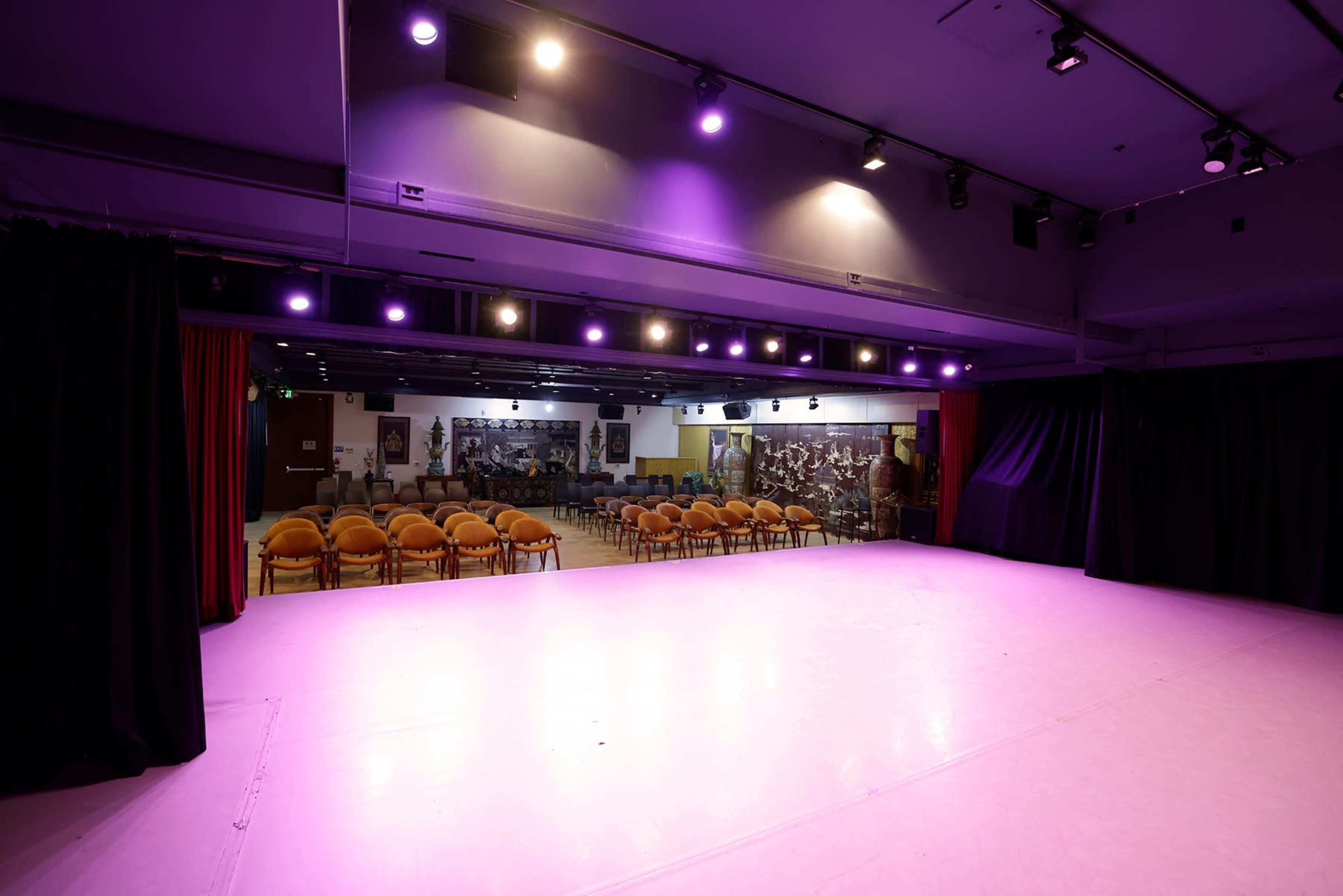 A stage area with bright lights and a seating arrangement of orange chairs facing it.
