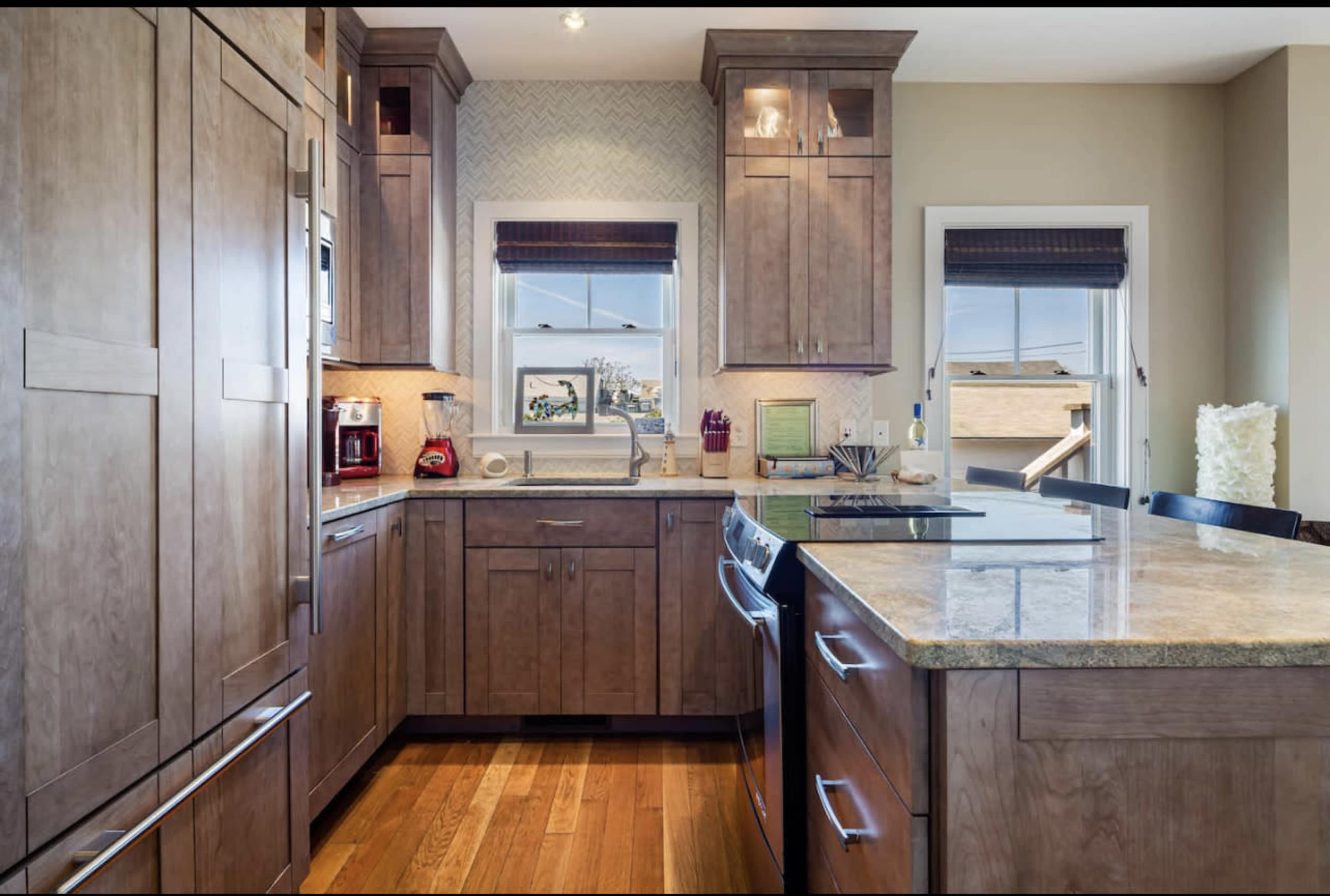 A modern kitchen with wooden cabinetry, a large island, and a window providing natural light.