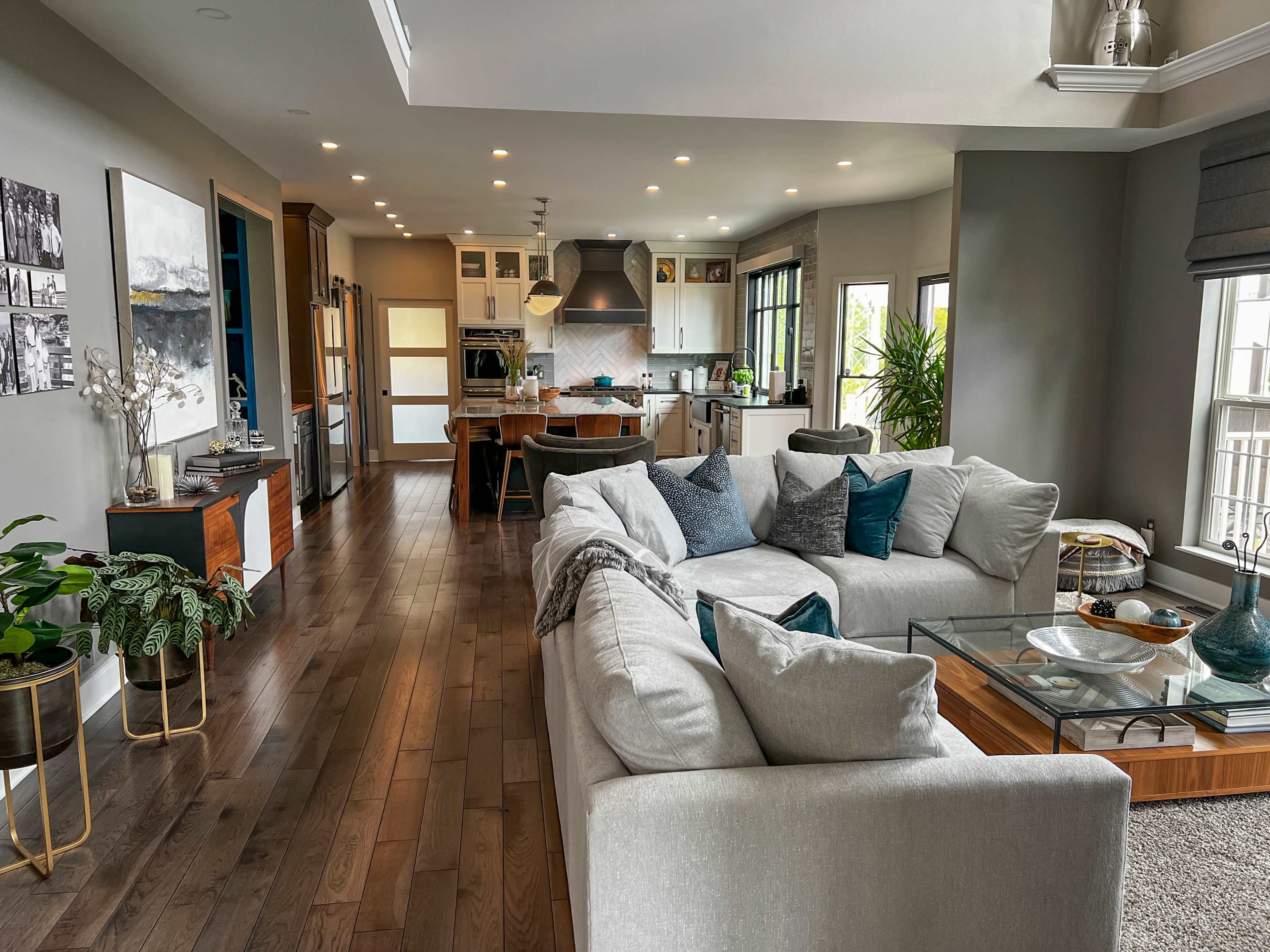 A modern open-concept living area with a large sectional sofa, dining space, and a kitchen featuring sleek cabinetry and a central island.