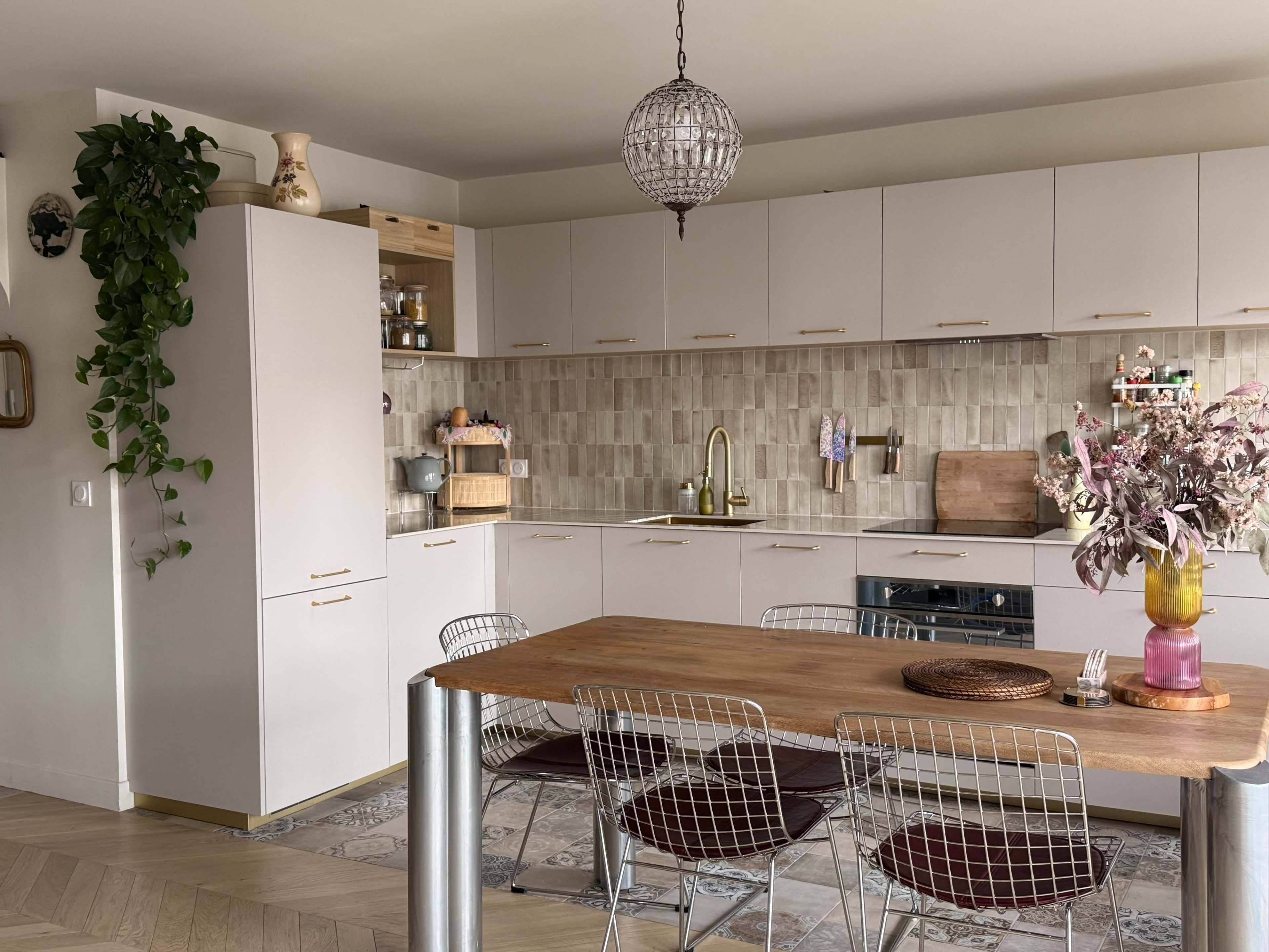The image features a modern kitchen with light-colored cabinets, a wooden dining table, and a patterned tile backsplash.