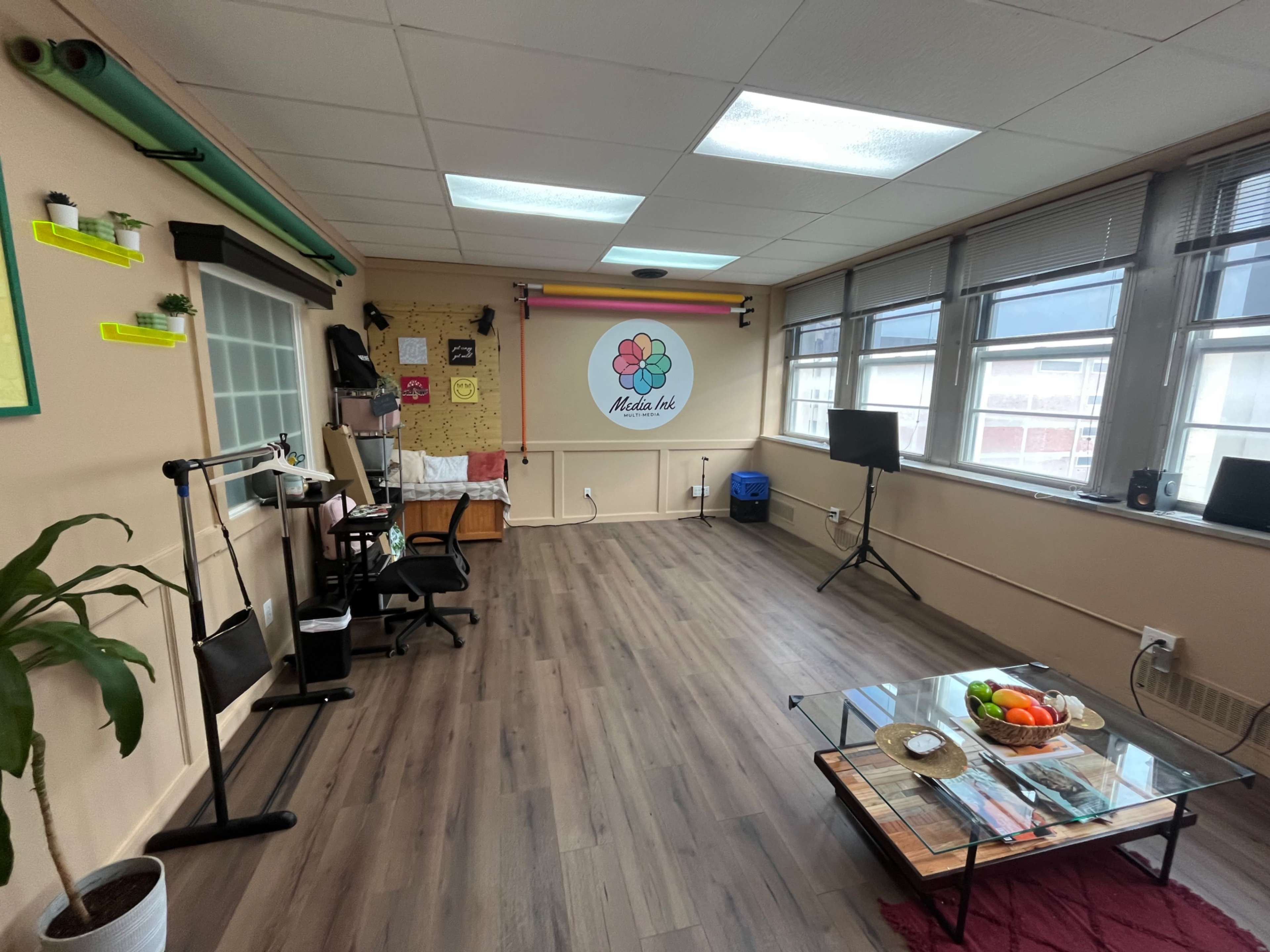A spacious, well-lit room with a seating area, a small table with fruit, and colorful wall decor.
