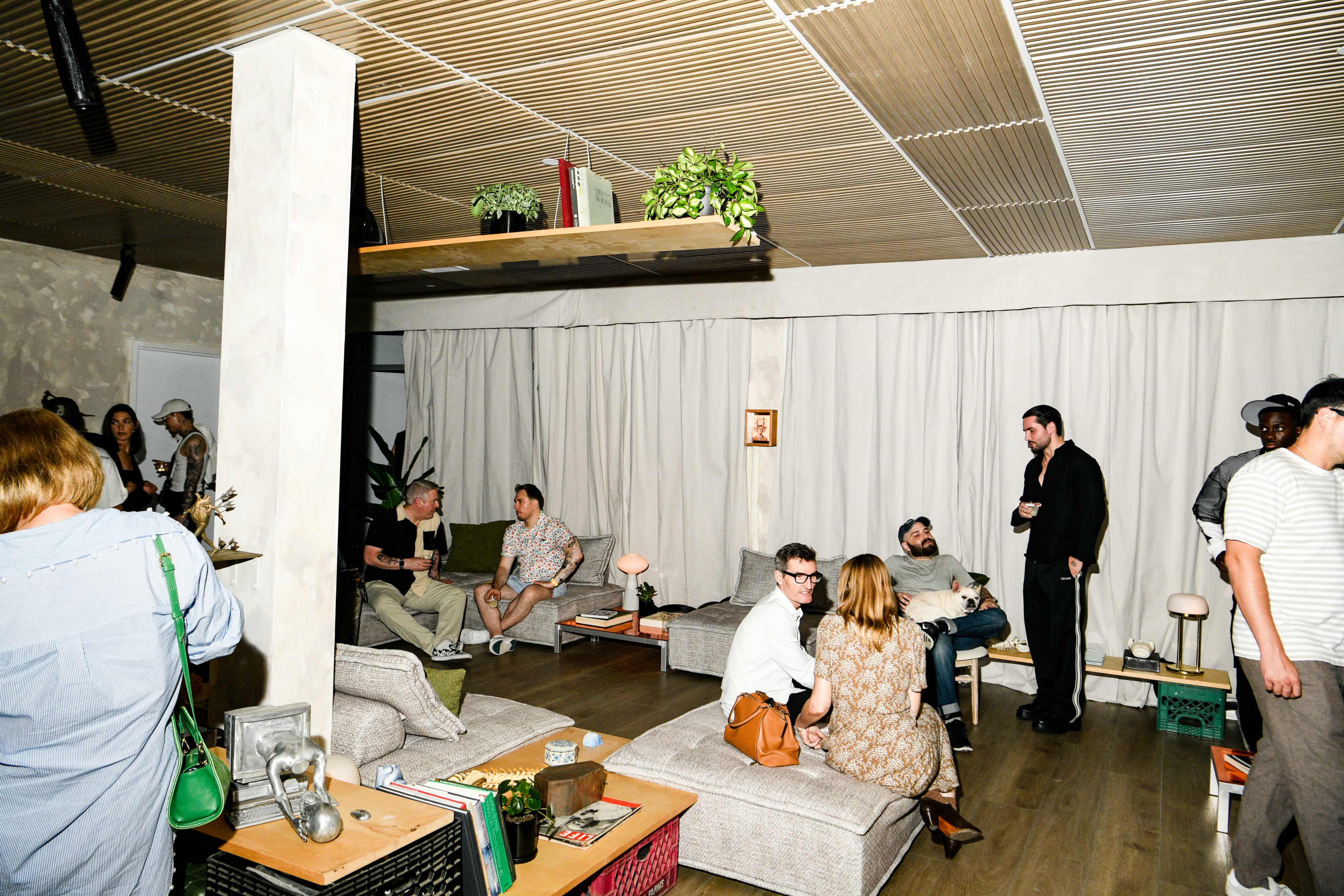 A group of people socializes in a well-lit lounge area with comfortable seating and soft lighting.