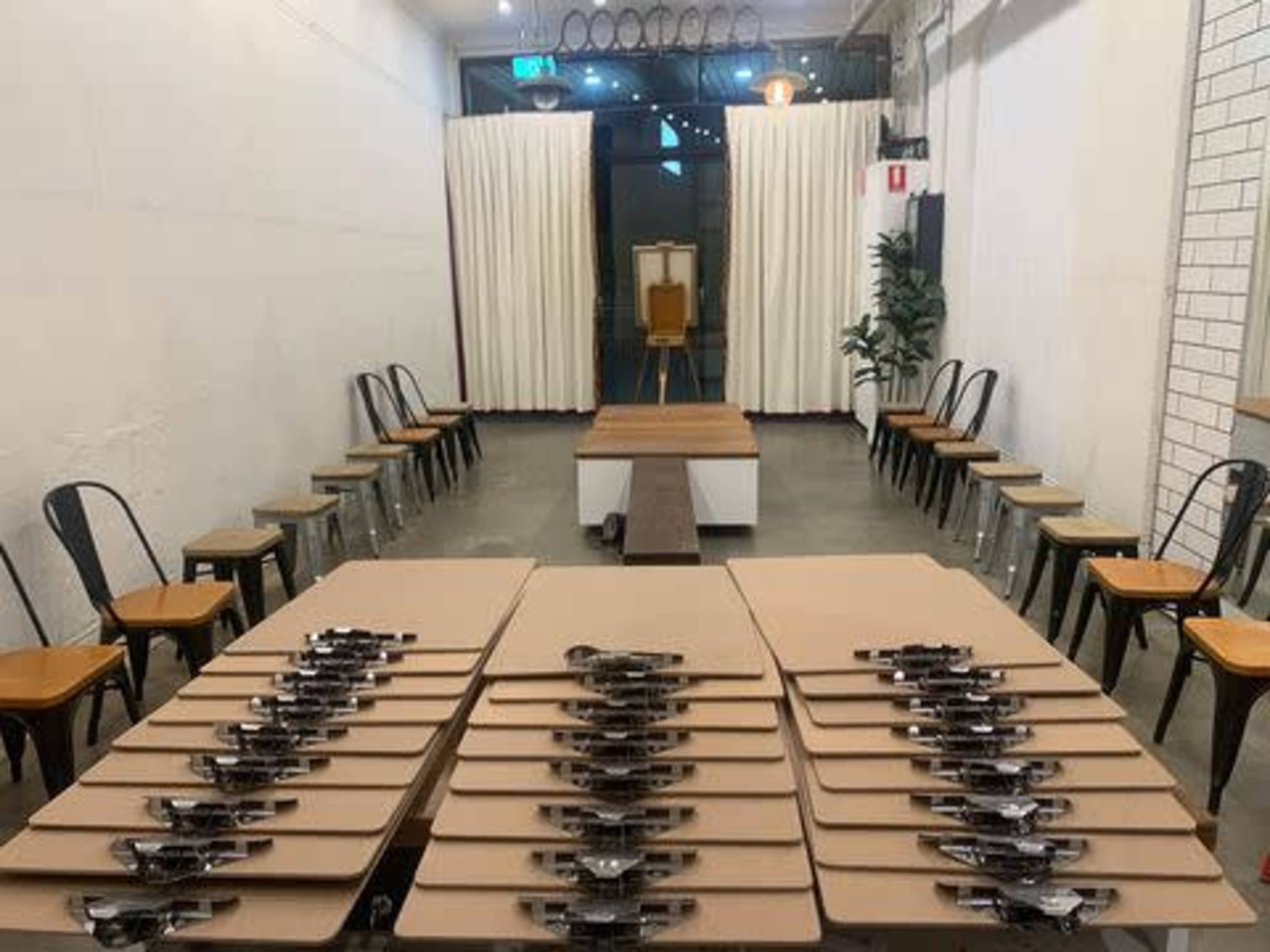A spacious room arranged with rows of chairs facing a central platform, with multiple clipboards neatly arranged on tables.