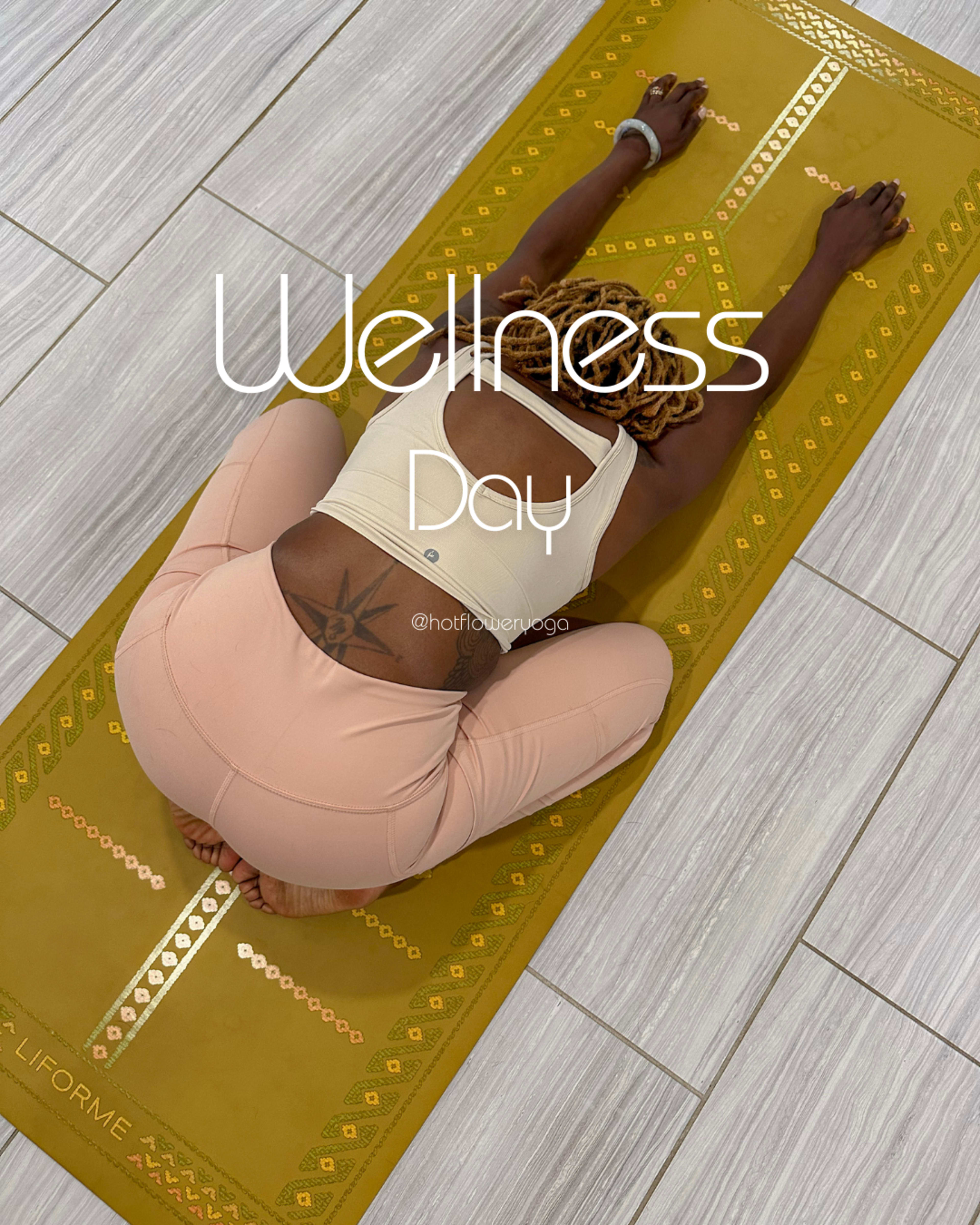 A person is practicing yoga on a yellow mat in a downward pose on a tiled floor with the text "Wellness Day" overlaid.
