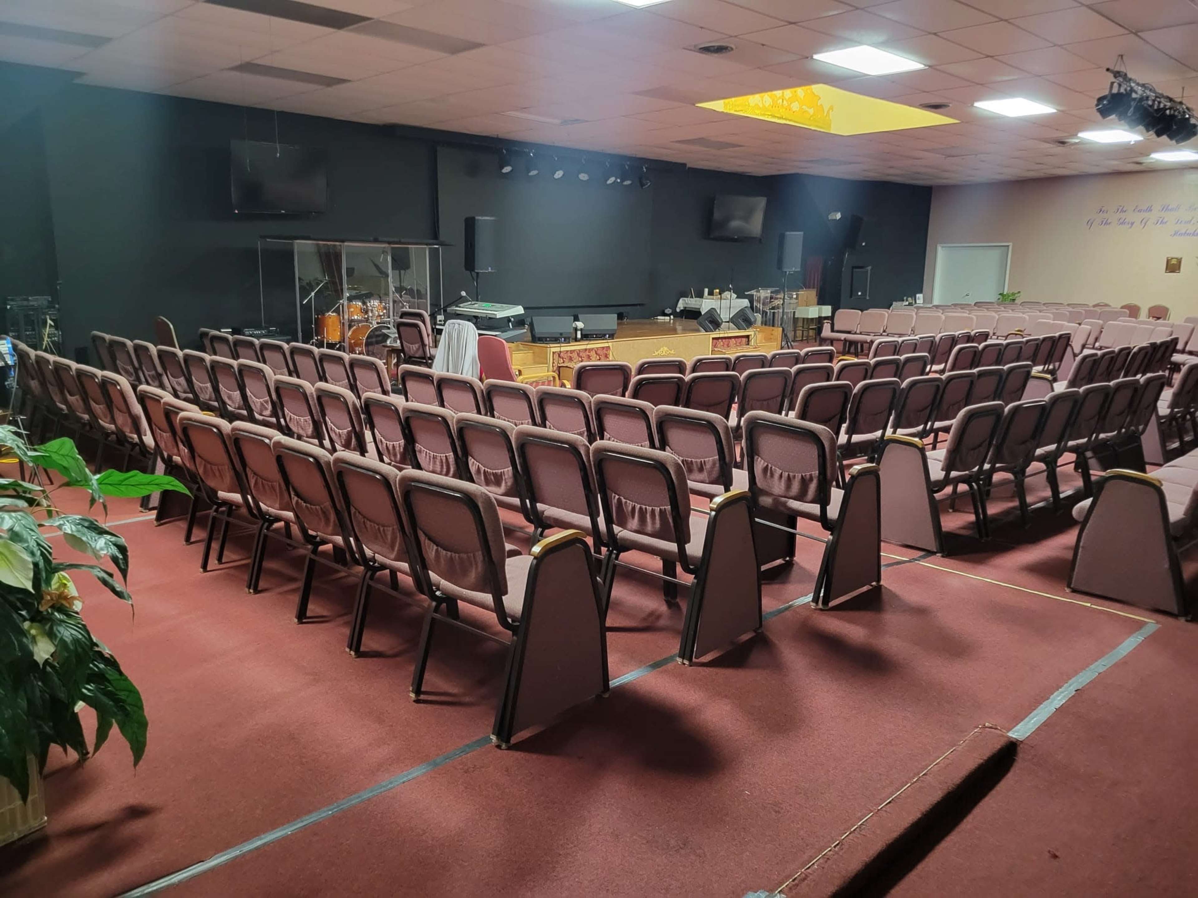 A church auditorium with rows of empty chairs facing a stage and musical instruments in the background.
