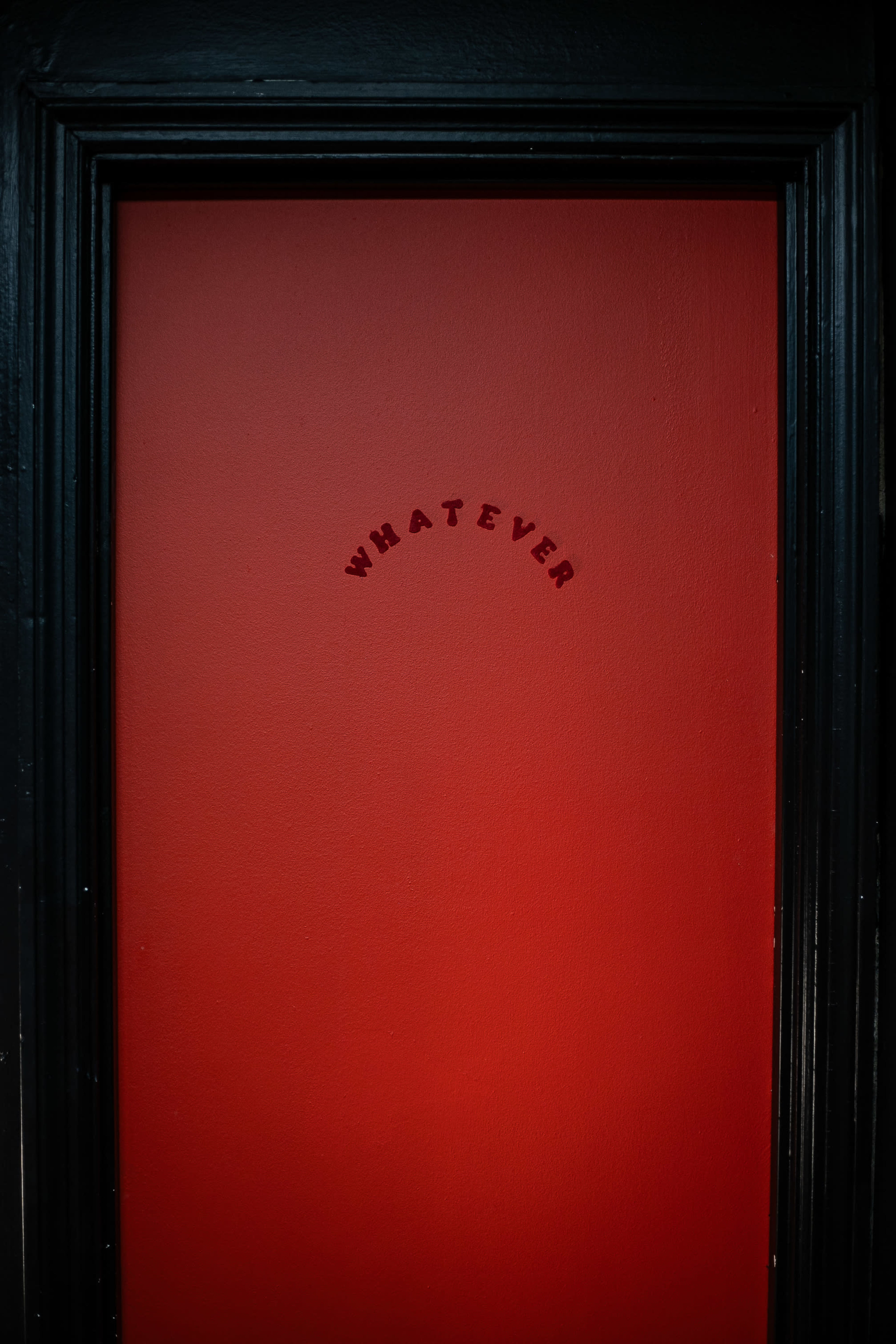 A red door with the word "WHATEVER" arched at the top is featured in the image.