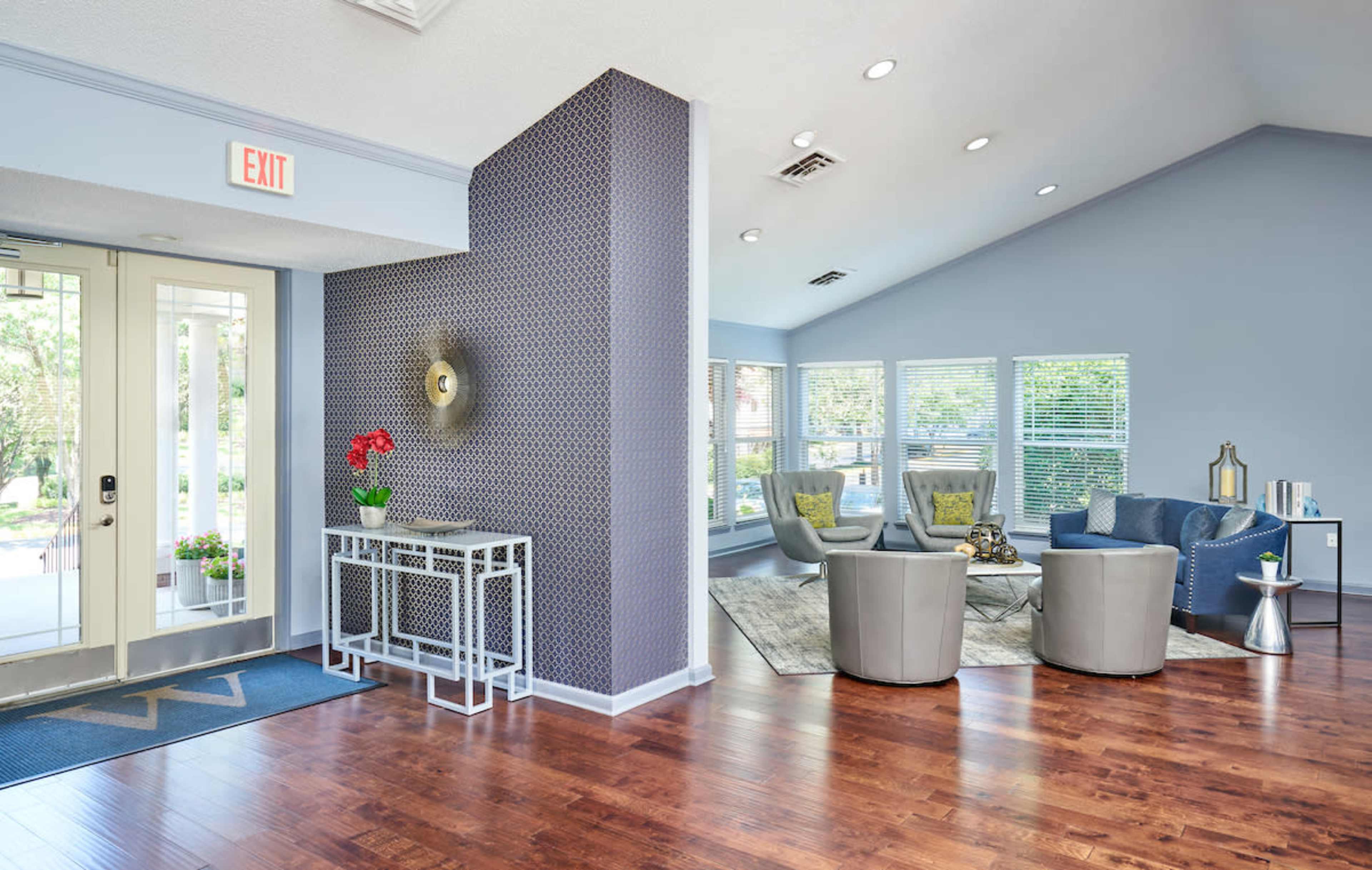 A reception area with a modern seating arrangement, large windows, and a stylish entrance.