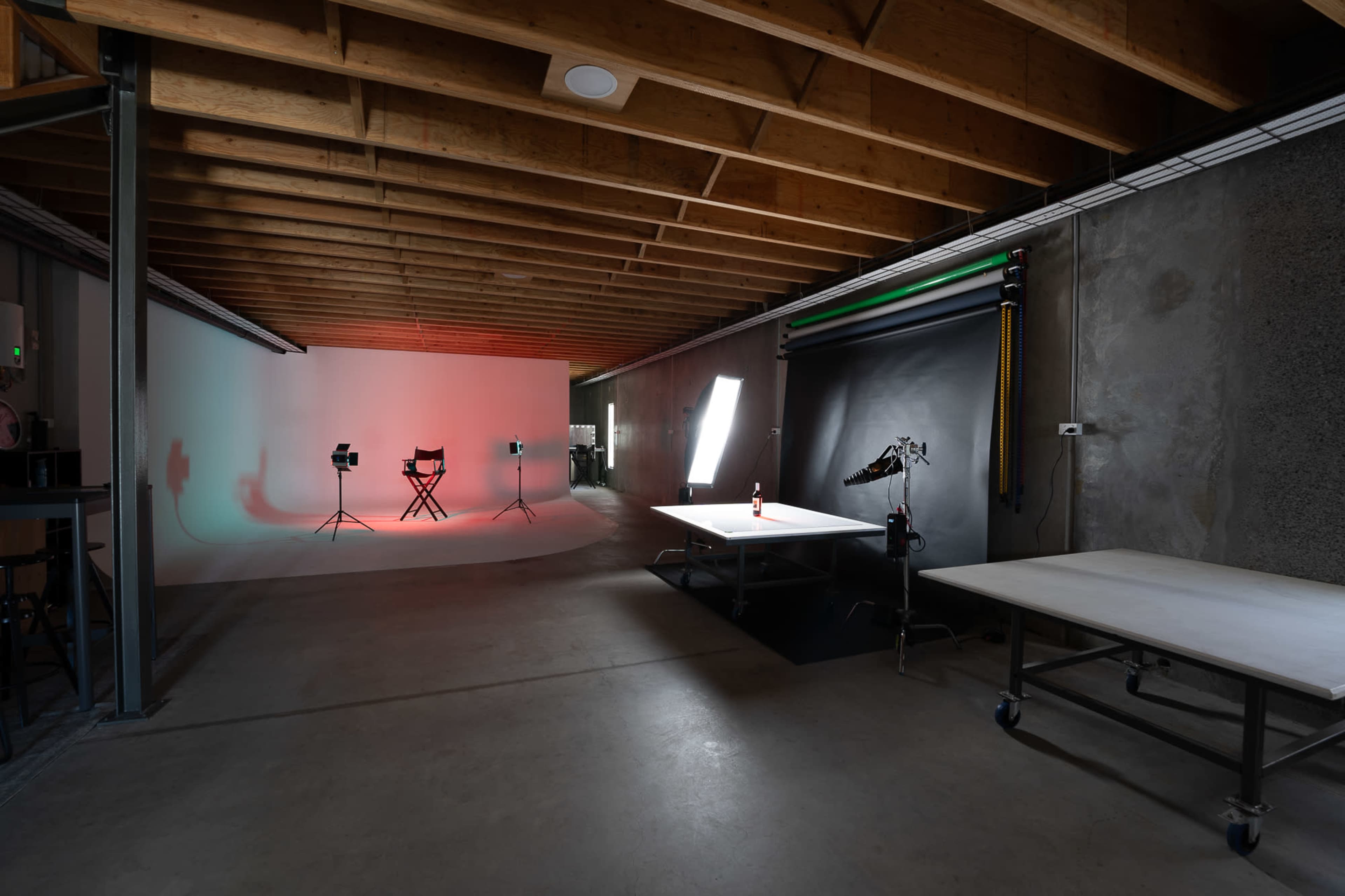 A spacious photography studio with a lit backdrop, a director's chair, and various equipment set up along the walls.