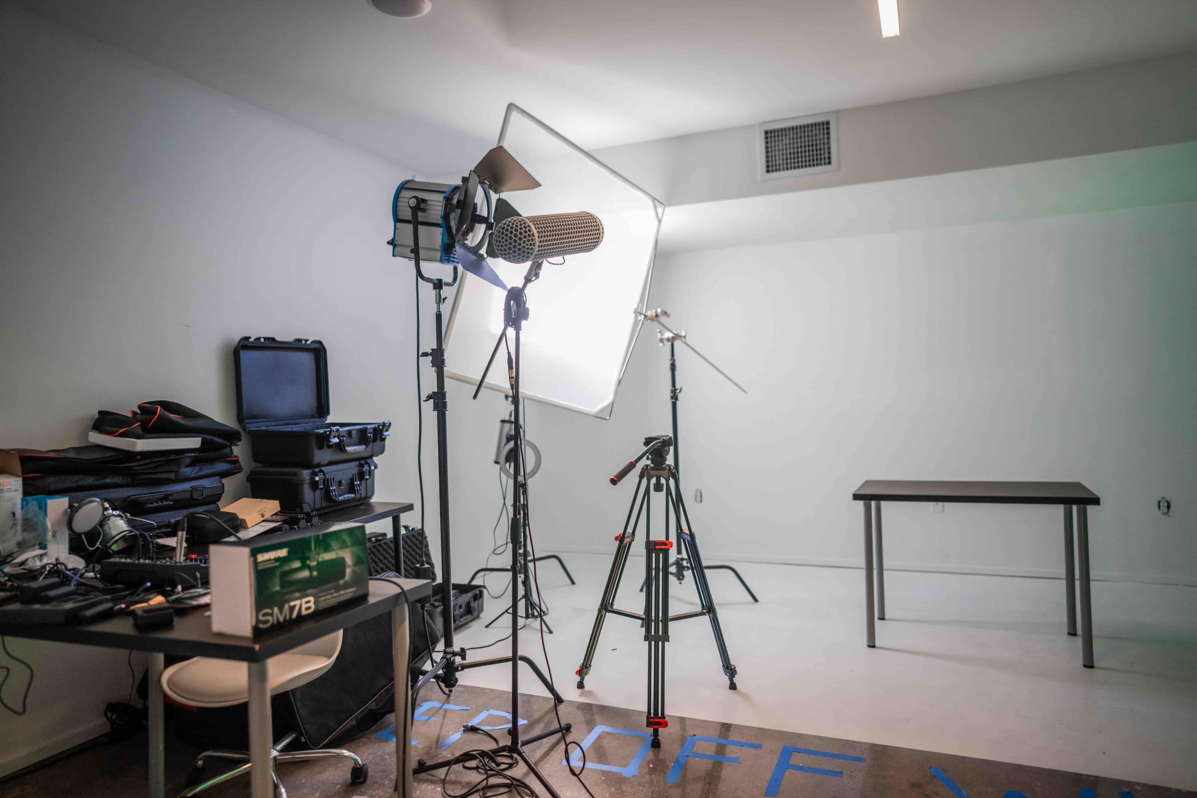 A photography studio is set up with lighting equipment, a microphone, and a table in a minimally furnished room.