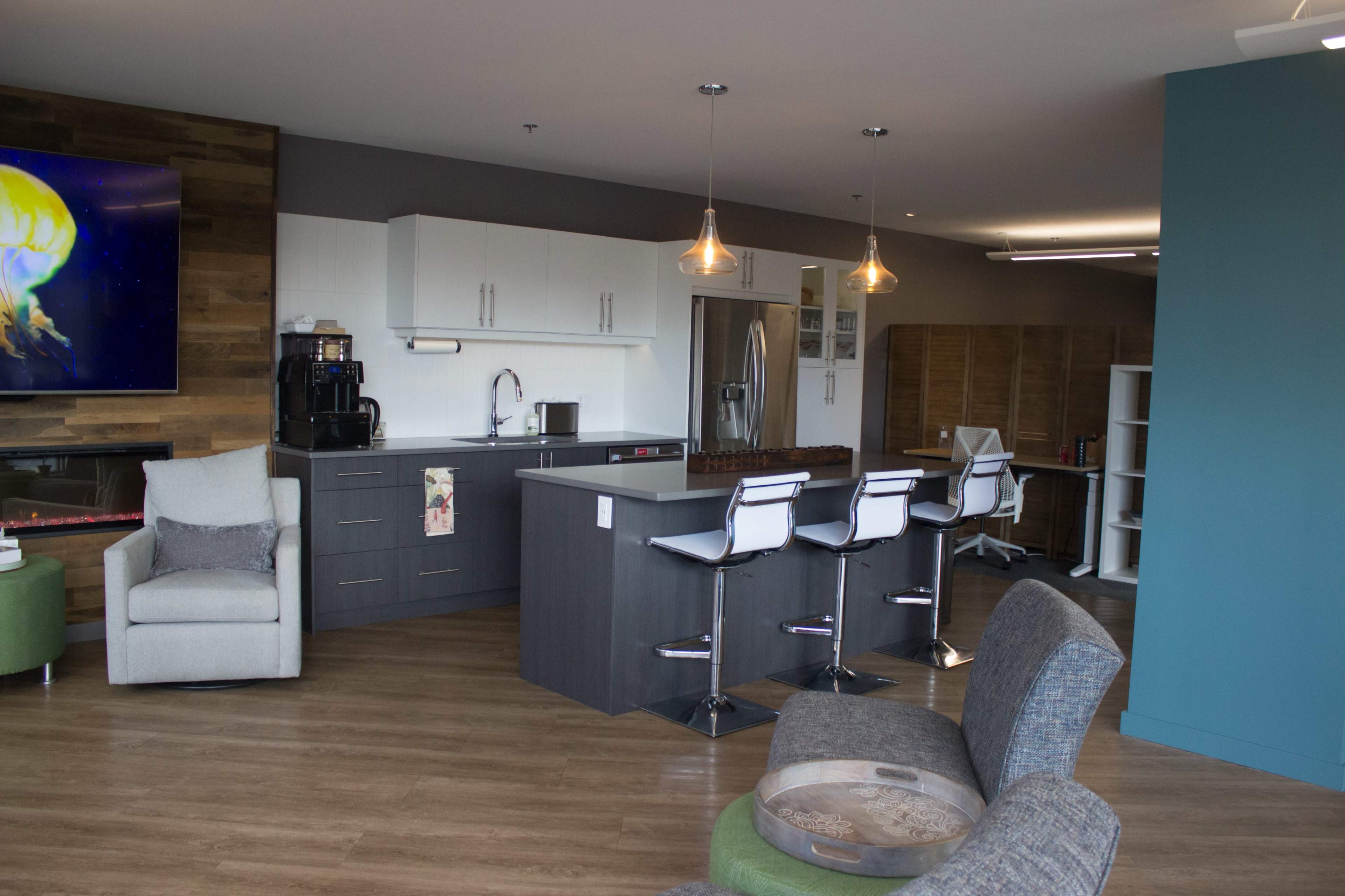 A modern kitchen and lounge area with a countertop, bar stools, and a seating arrangement.