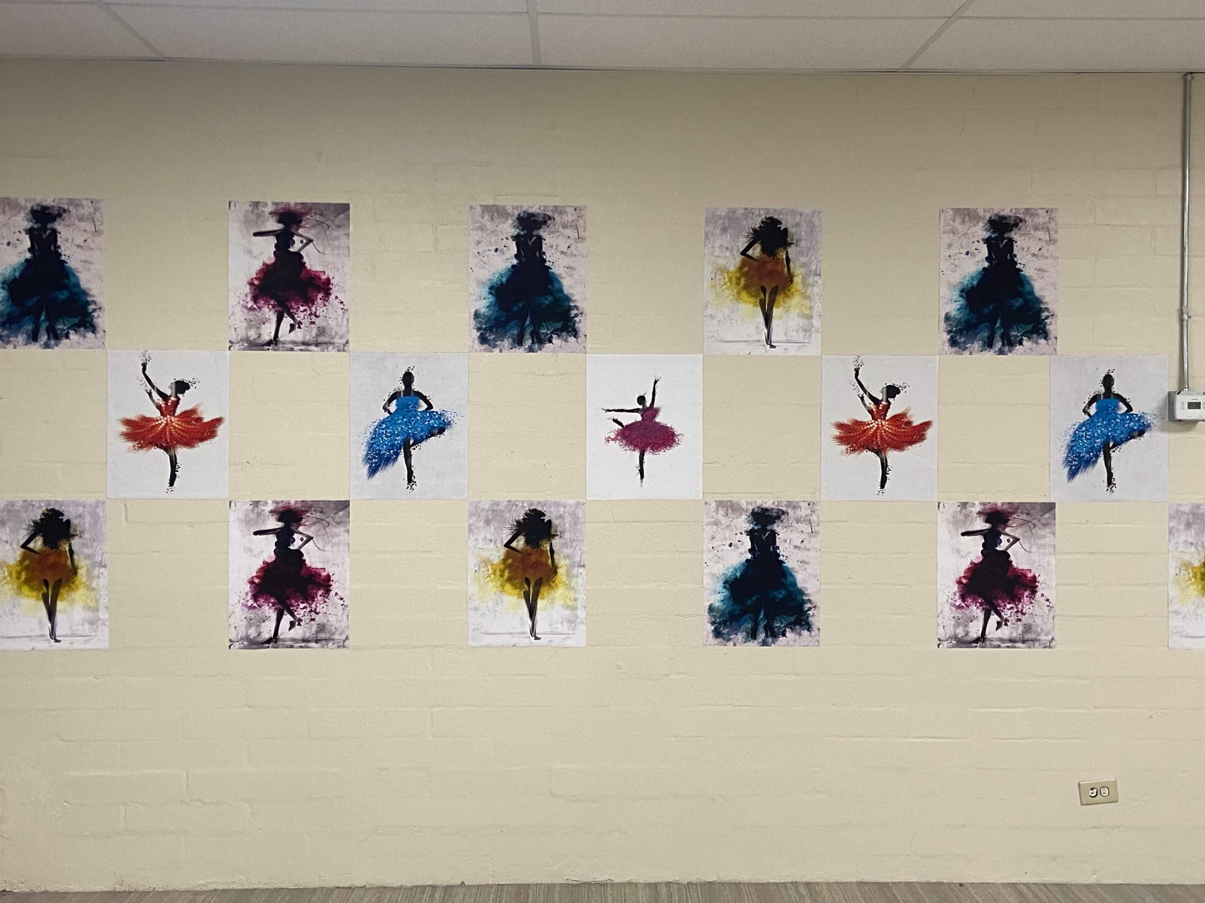 A wall decorated with several framed artworks depicting silhouetted dancers in various colored dresses.