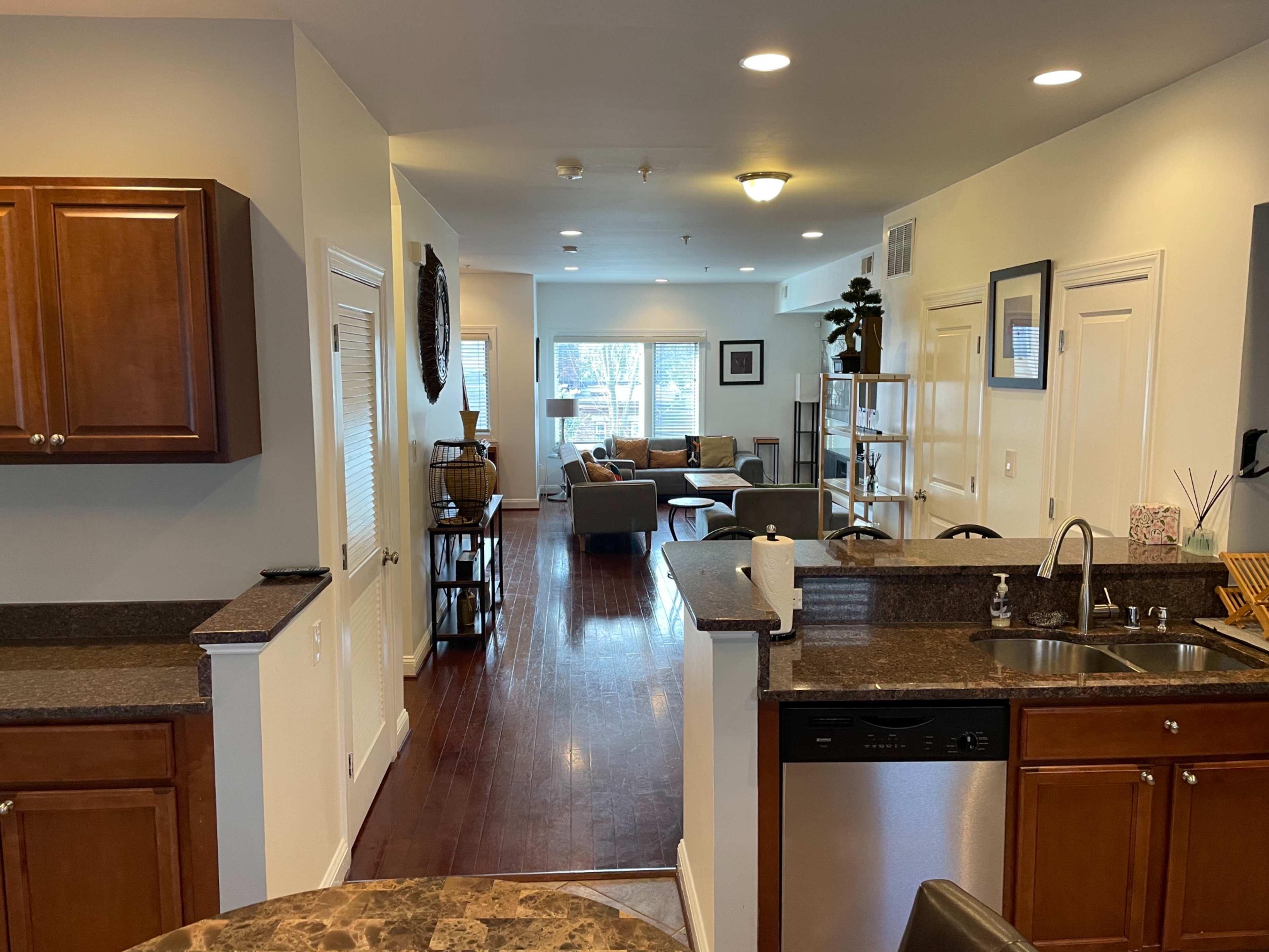 A modern open-concept living space featuring a kitchen with wooden cabinets, a dining area, and a living room with ample natural light and furniture.