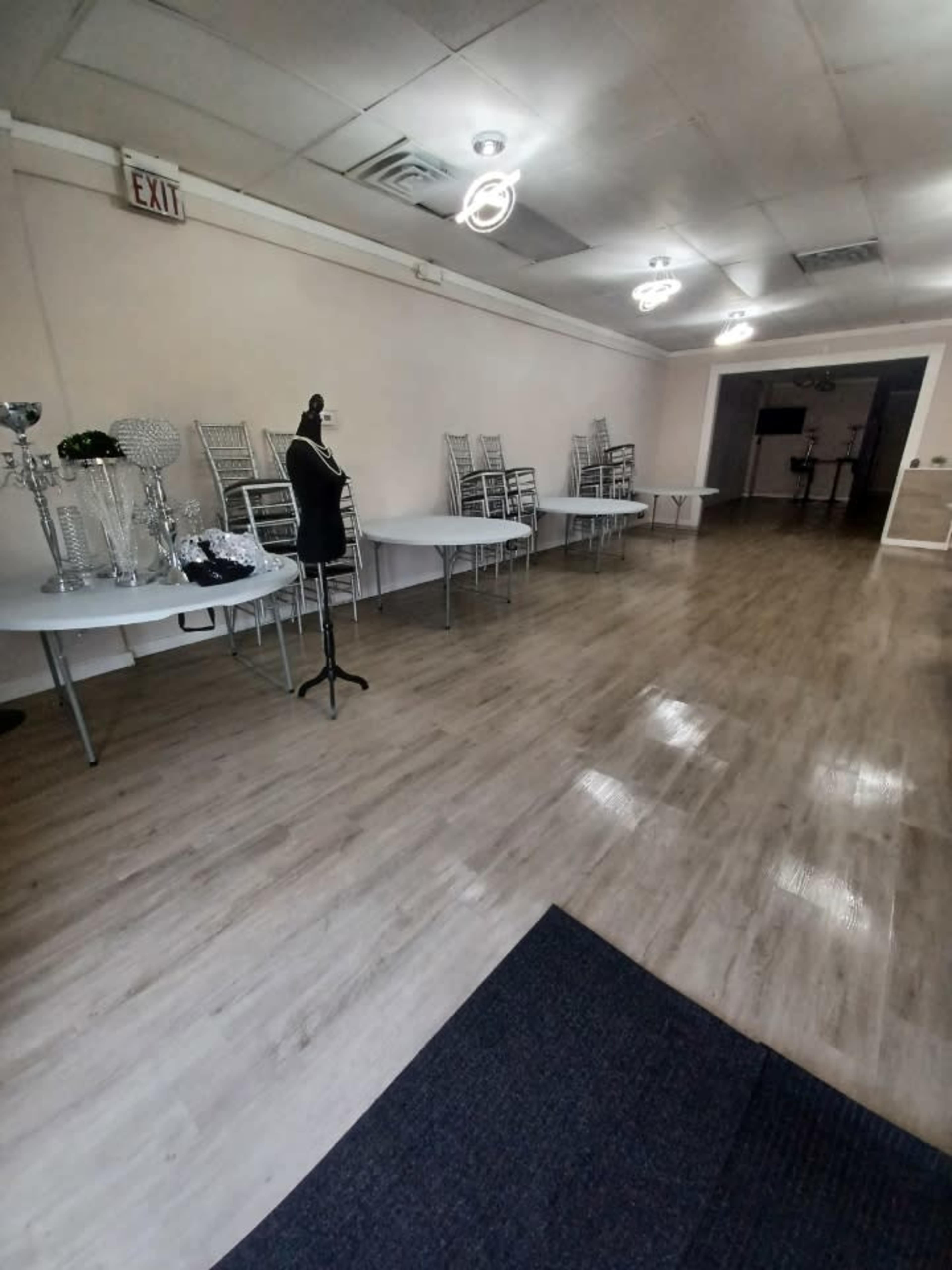 A spacious event venue with neatly arranged tables and chairs, a mannequin, and decorative items on display.